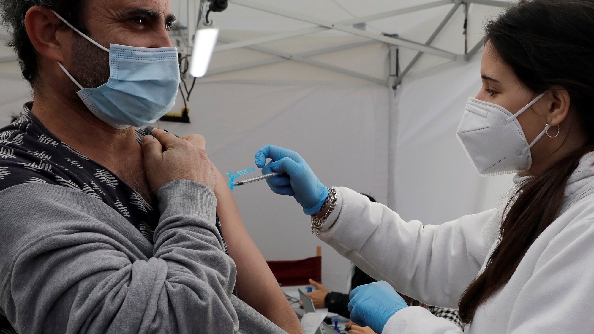 epa09626985 A man receives a dose of Covid-19 vaccine at a makeshift vaccination booth in Valencia, Spain, 07 December 2021.  EPA/Juan Carlos Cardenas