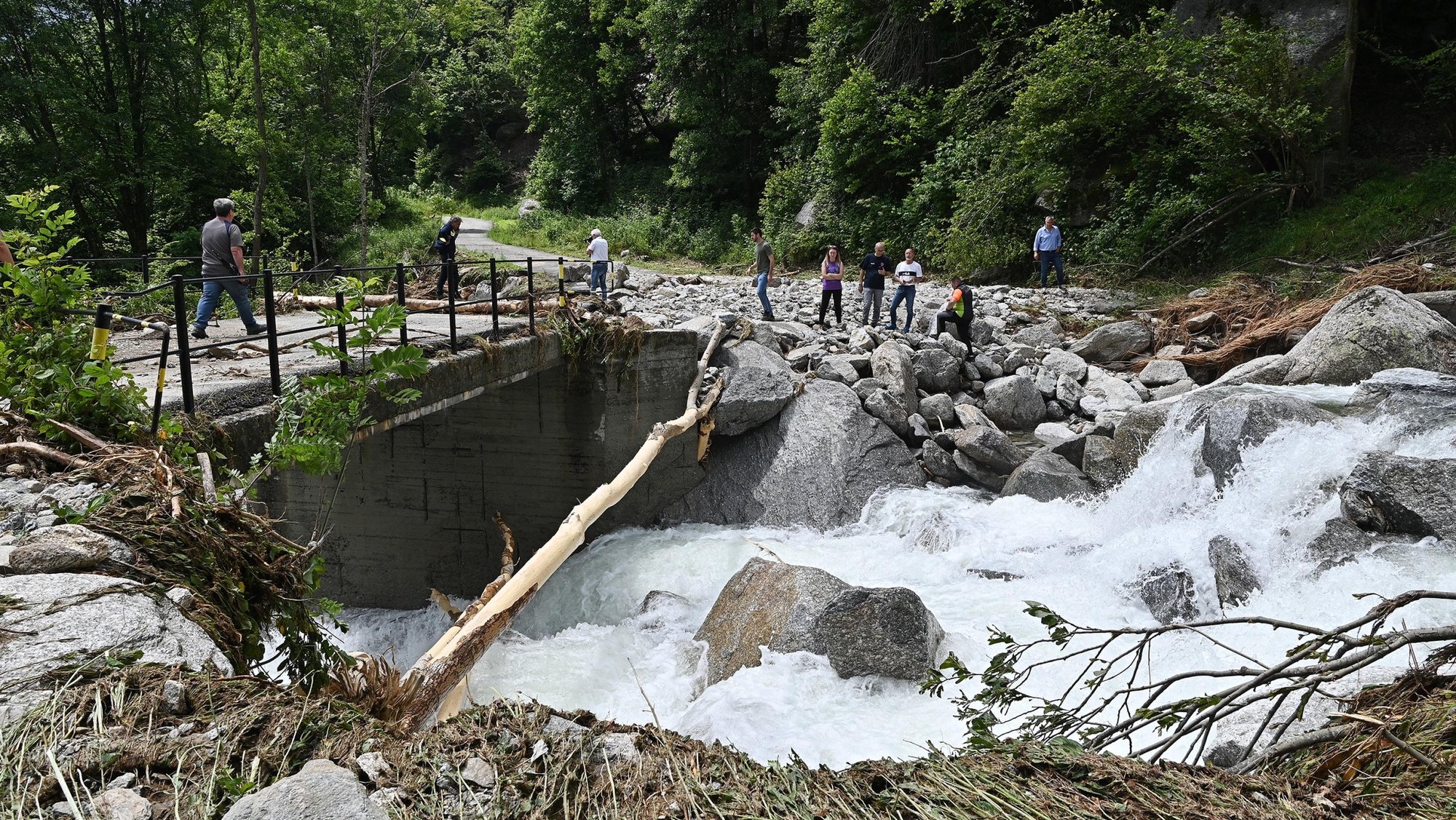 epa11447466 People look at an area damaged by flooding in Chialamberto, Lanzo Valley, near Turin, Italy, 30 June 2024. Dozens of people had to leave their residence in the alpine valleys of Turin. Severe weather hit northern Italy, in particular Aosta Valley and Piedmont, leaving extensive damage due to landslides and floods. The town of Cogne remains isolated as the only road to reach it was heavily damaged in several places.  EPA/ALESSANDRO DI MARCO