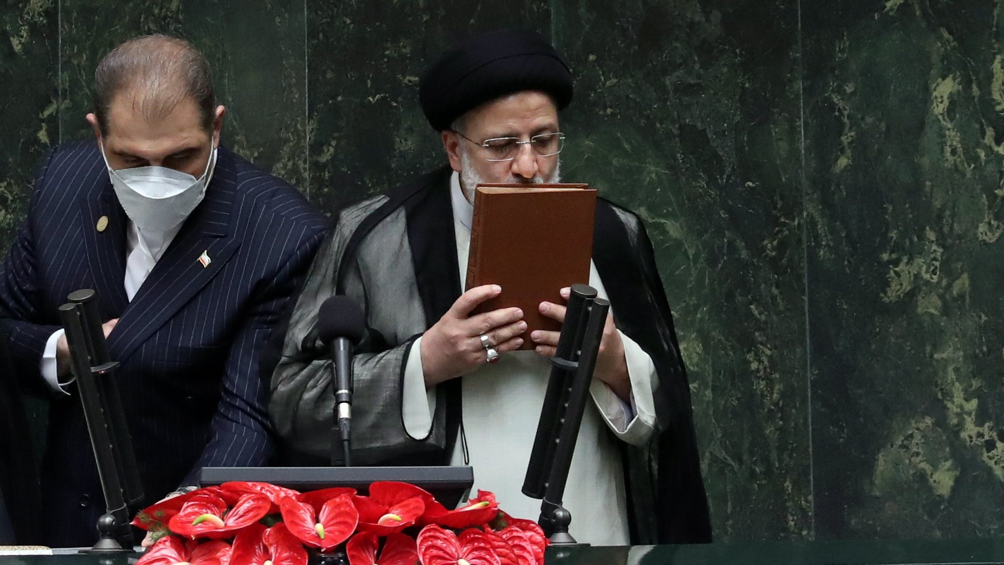 epa09398424 Iranian President Ebrahim Raisi (R) kisses the holy Koran after being sworn-in for his first four-year term of presidency at the parliament in Tehran, Iran, 05 August 2021.  Iran&#039;s new president Ebrahim Raisi was sworn in on 05 August before parliament in Tehran in a ceremony that foreigners attended for the second time since the Islamic Revolution in 1979. Raise is to present his cabinet to the 290-seat parliament for approval in the next week.  EPA/ABEDIN TAHERKENAREH