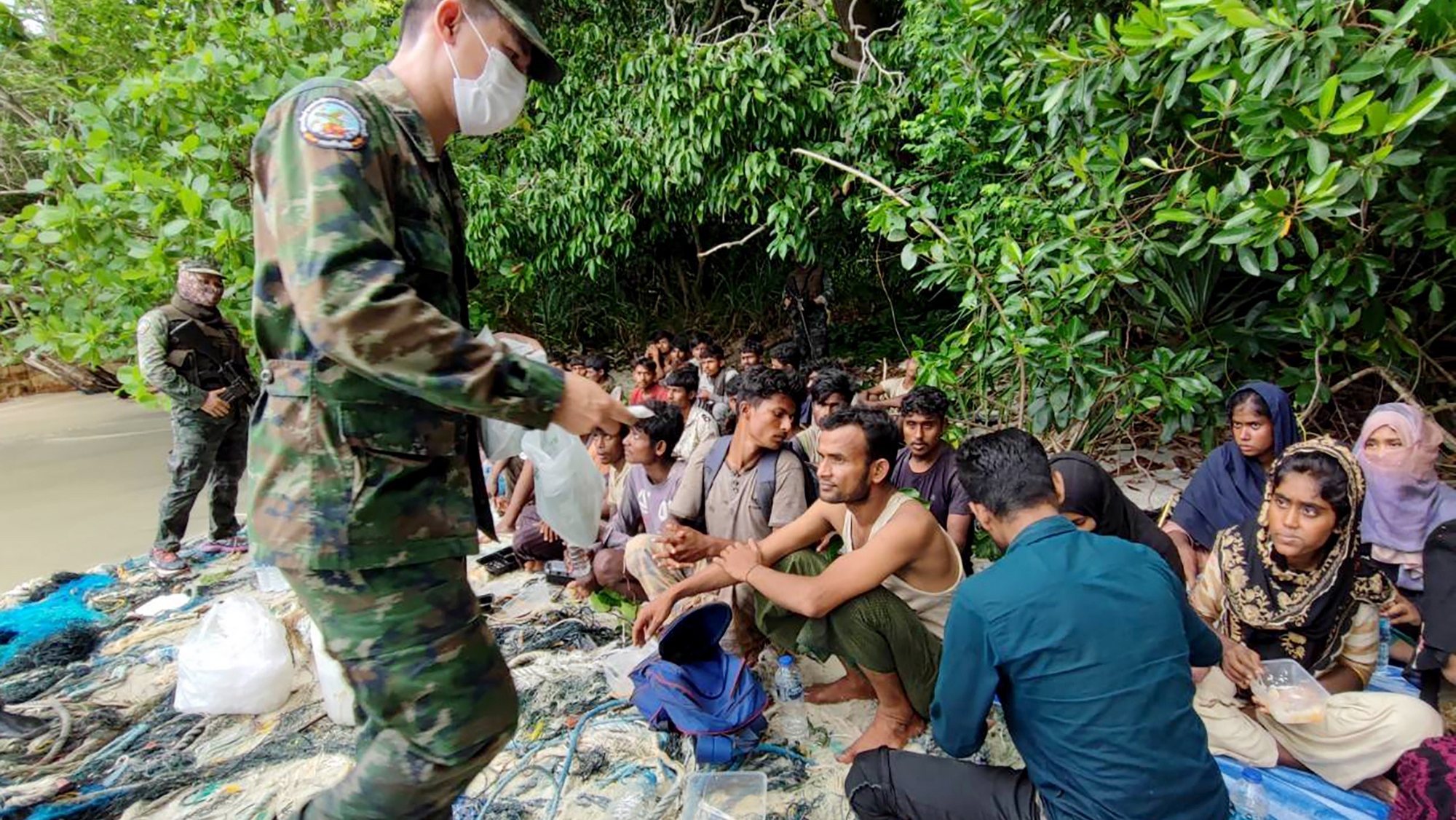 epa09996854 A handout photo released by Royal Thai Navy shows a Thai soldier assisting Rohingya refugees after being found on Dong island, near the Thai-Malaysia border in Satun southernmost province of Thailand, 04 June 2022 (issued 05 June 2022). Thai officials and Royal Navy found and assisted 59 undocumented Rohingya migrants on an island in southern Thailand. The migrants, through human trafficking gangs, arrived to Thailand in vessels, hoping to reach Malaysia afterwards to find work.  EPA/ROYAL THAI NAVY HANDOUT EDITORIAL USE ONLY/ NO SALES HANDOUT EDITORIAL USE ONLY/NO SALES