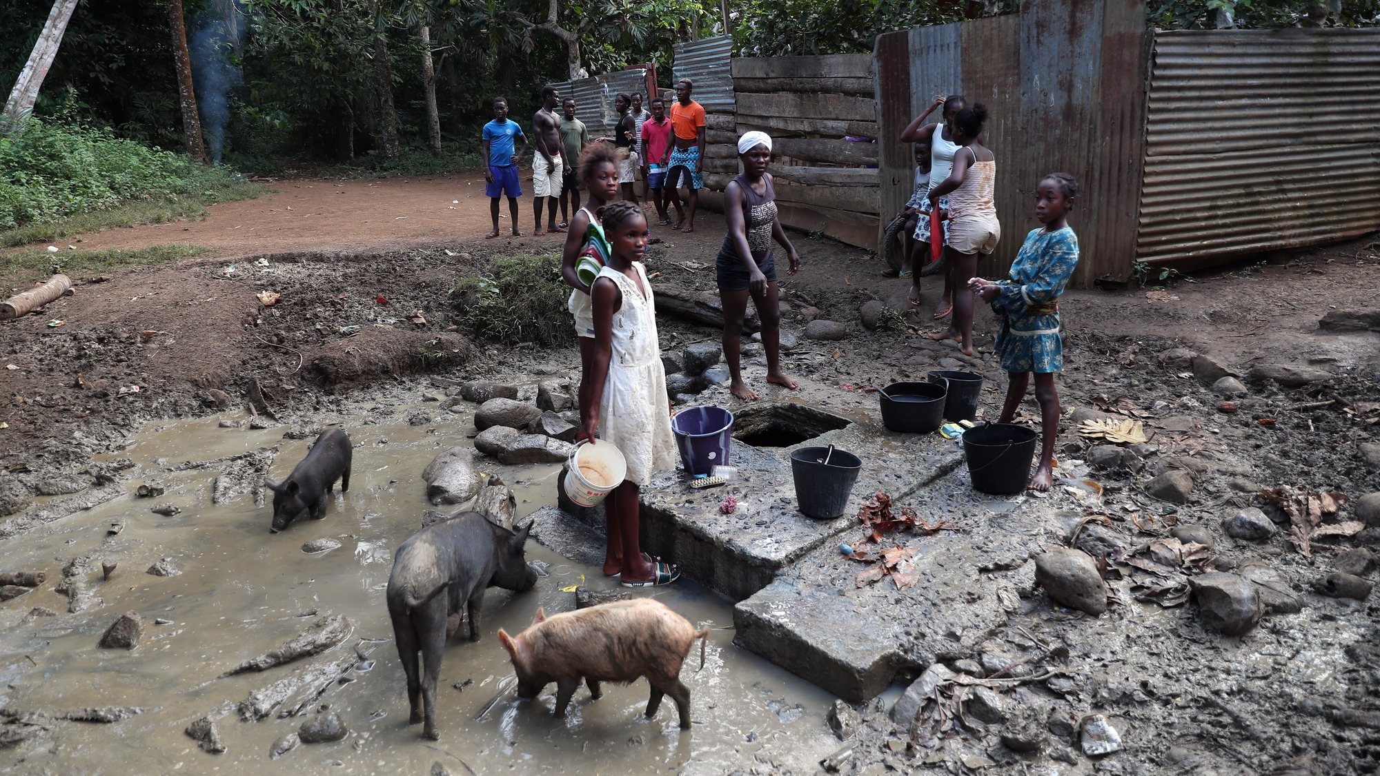 epa09352643 Children draw water for consumption from a spring, as they have no piped water, in Messias Alves Beach, Sao Tome Island, Sao Tome and Principe, 18 July 2021. Inhabitants of Praia Messias Alves, Cantagalo district, carried out an electoral boycott on 18 July, cutting the road, not allowing the ballot boxes to access the planned location, demanding better roads, electricity and piped water. With pieces of scrap metal, sticks and tree branches, the population set up a barricade during the night and prevented access to the polling station, which should have taken place in a tent set up a little further up the road, in a courtyard.  EPA/NUNO VEIGA