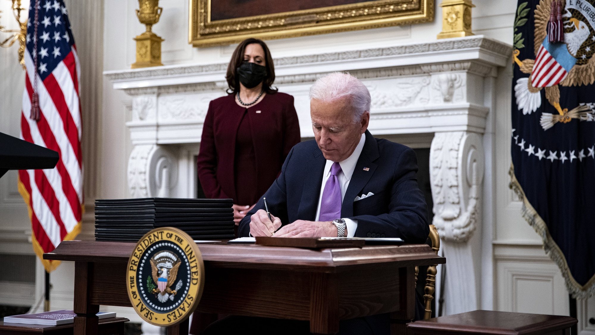 epa08956525 US President Joe Biden signs an executive order after speaking during an event on his administration&#039;s Covid-19 response with U.S. Vice President Kamala Harris, left, in the State Dining Room of the White House in Washington, DC, USA, on 21 January 2021. Biden in his first full day in office plans to issue a sweeping set of executive orders to tackle the raging Covid-19 pandemic to rapidly reverse or refashion many of his predecessor&#039;s most heavily criticized policies.  EPA/Al Drago / POOL