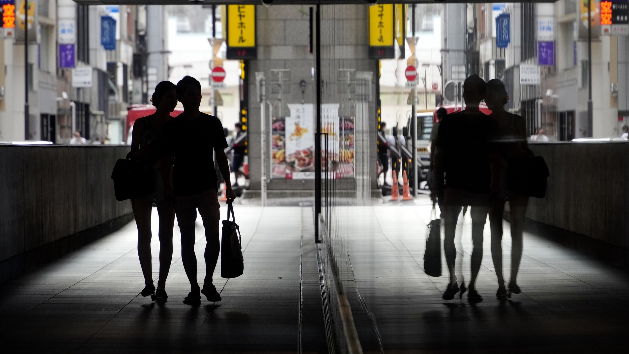 epa10187624 A couple is reflected on a mirror as they walk through an underpass in Tokyo, Japan, 16 September 2022. The government-affiliated National Institute of Population and Social Security published in September 2022 the results of a 2021 survey, showing that a record number of people - one in four - between 18 and 34 years of age have no plans to ever get married, citing loss of freedom and financial worries.  EPA/FRANCK ROBICHON