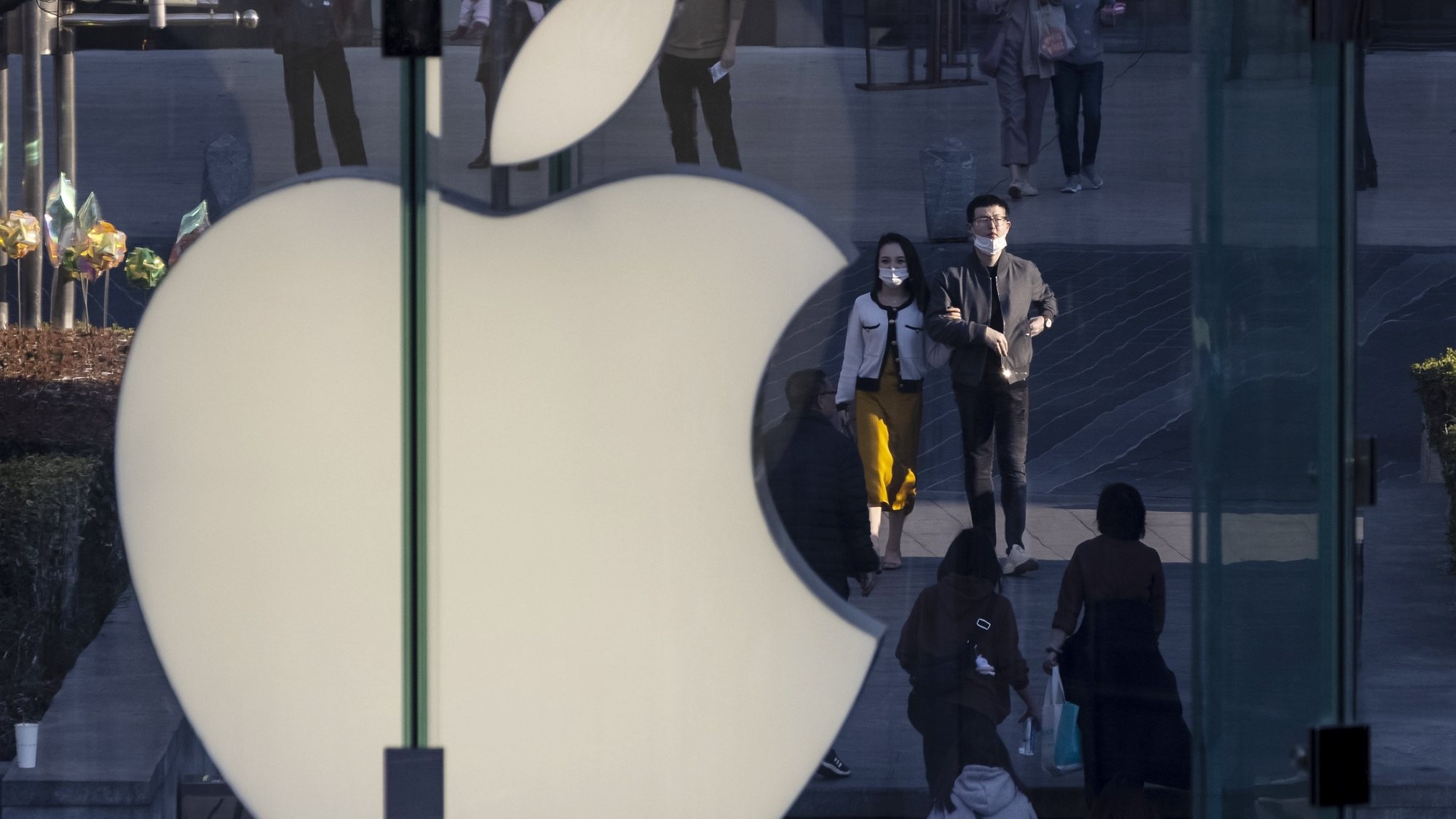 epa09027457 People walk next to the Apple logo in the  financial district of Shanghai, China, 21 February 2021. Provinces in China have set the growth targets to be over 6.5 per cent for 2021 before the annual session of the National People&#039;s Congress set for 04 March in Beijing. China&#039;s economy grew 2.3 per cent in 2020 despite the COVID-19 pandemic, according to data from the National Bureau that was released in January 2021.  EPA/ALEX PLAVEVSKI