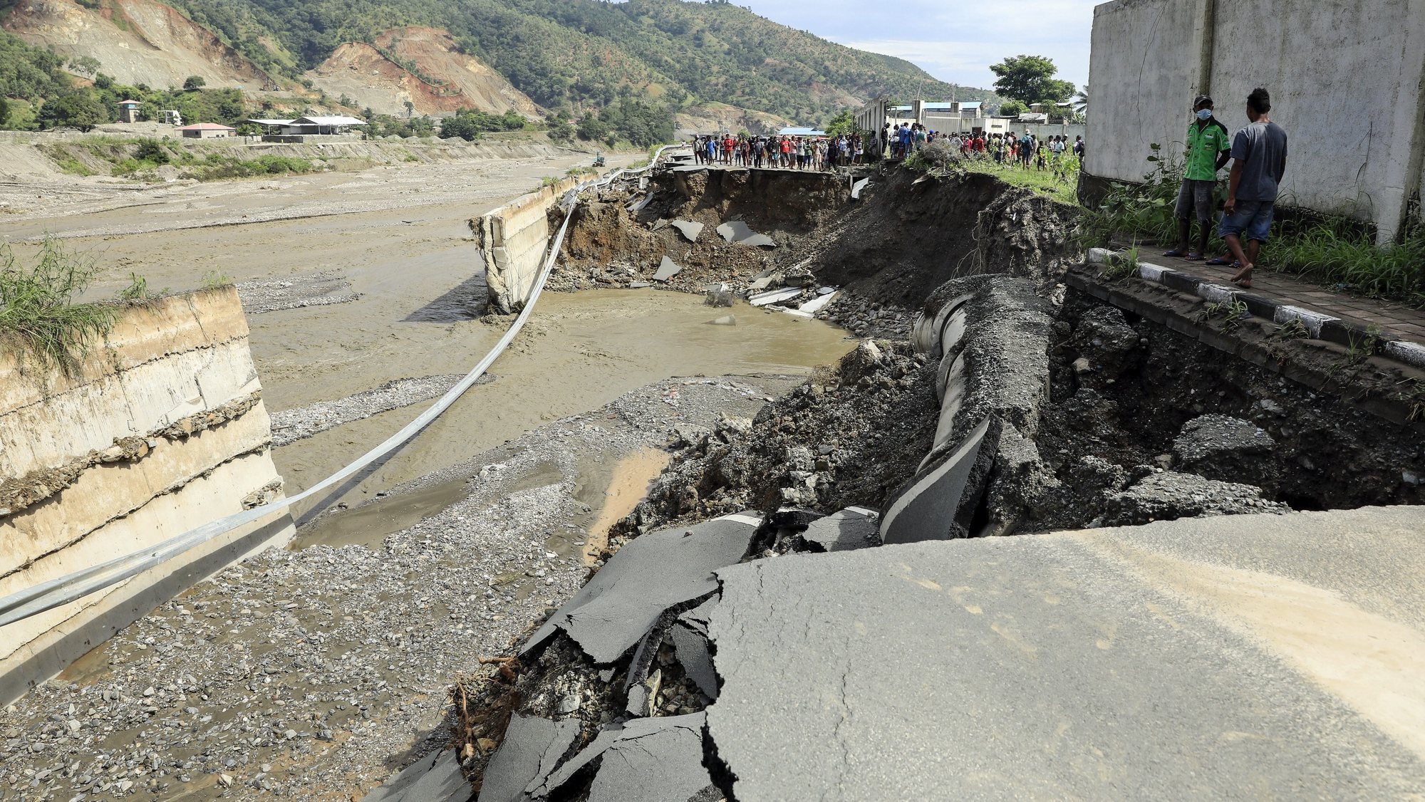 epa09117913 People gather near a damaged road in the aftermath of floods in Dili, East Timor, also known as Timor Leste, 06 April 2021. More than 150 people have been killed in eastern part of Indonesia and neighbouring East Timor, after floods and Seroja tropical cyclone hit the region, leaving dozens of people missing and thousands homeless.  EPA/ANTONIO DASIPARU