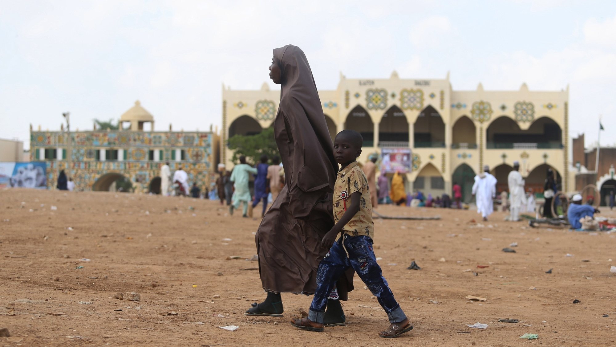 epa09200615 A Muslim woman walks past with her child in front of the Emir of Zaria&#039;s palace in northern Nigeria 14 May 2021. Muslims around the world are celebrating Eid al-Fitr, the three day festival marking the end of the Muslim holy fasting month of Ramadan. Eid al-Fitr is one of the two major holidays in Islam.  EPA/AKINTUNDE AKINLEYE