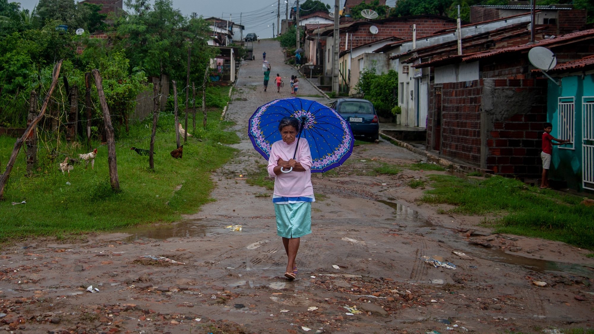 Uma mulher que caminha numa rua afetada pelas cheias no Brasil