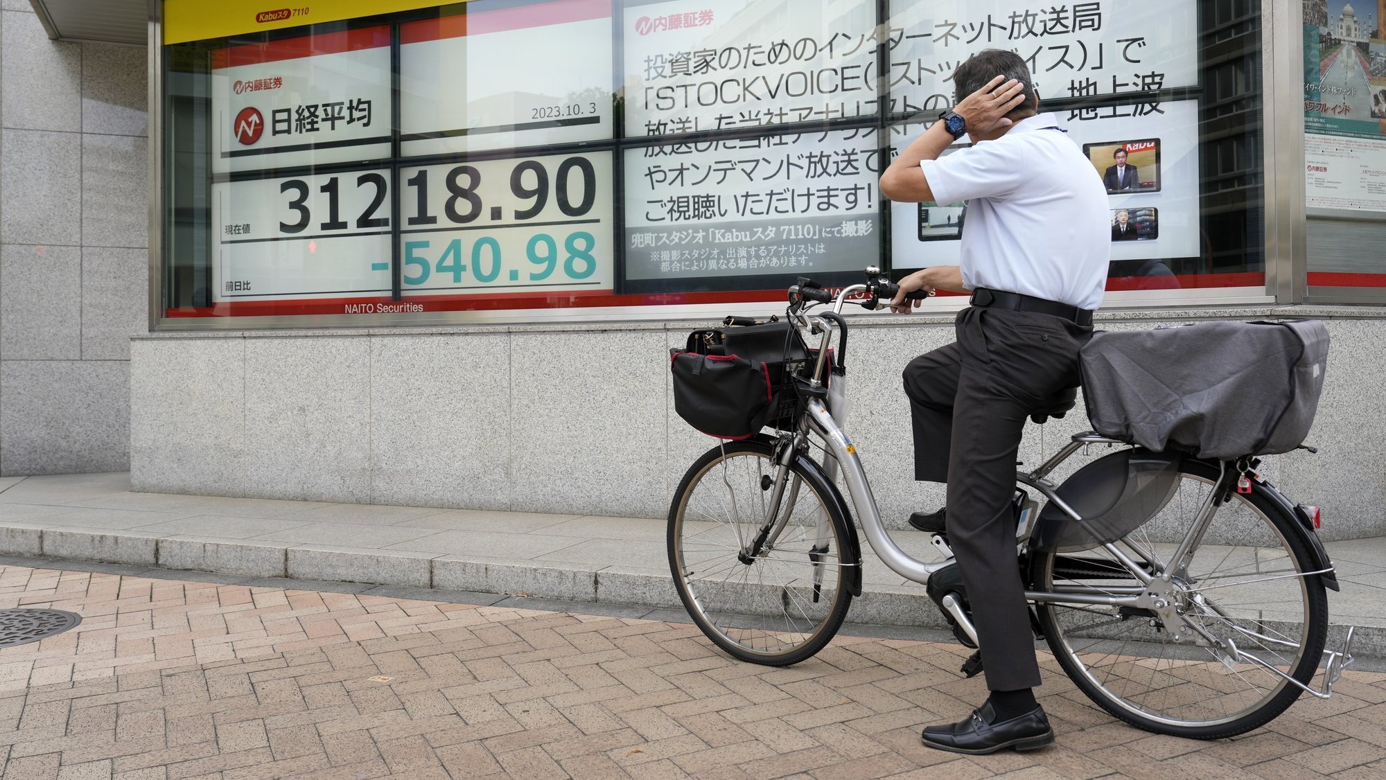 epaselect epa10896731 A man sitting on bicycle looks at a stock market indicator board in Tokyo, Japan, 03 October 2023. Tokyo&#039;s Nikkei Stock Average closed lower for a fourth consecutive day amid concerns on the US Federal Reserve interest rates. The yen continued its fall against the US dollar approaching the 150 yen mark for a dollar in the afternoon trading.  EPA/FRANCK ROBICHON
