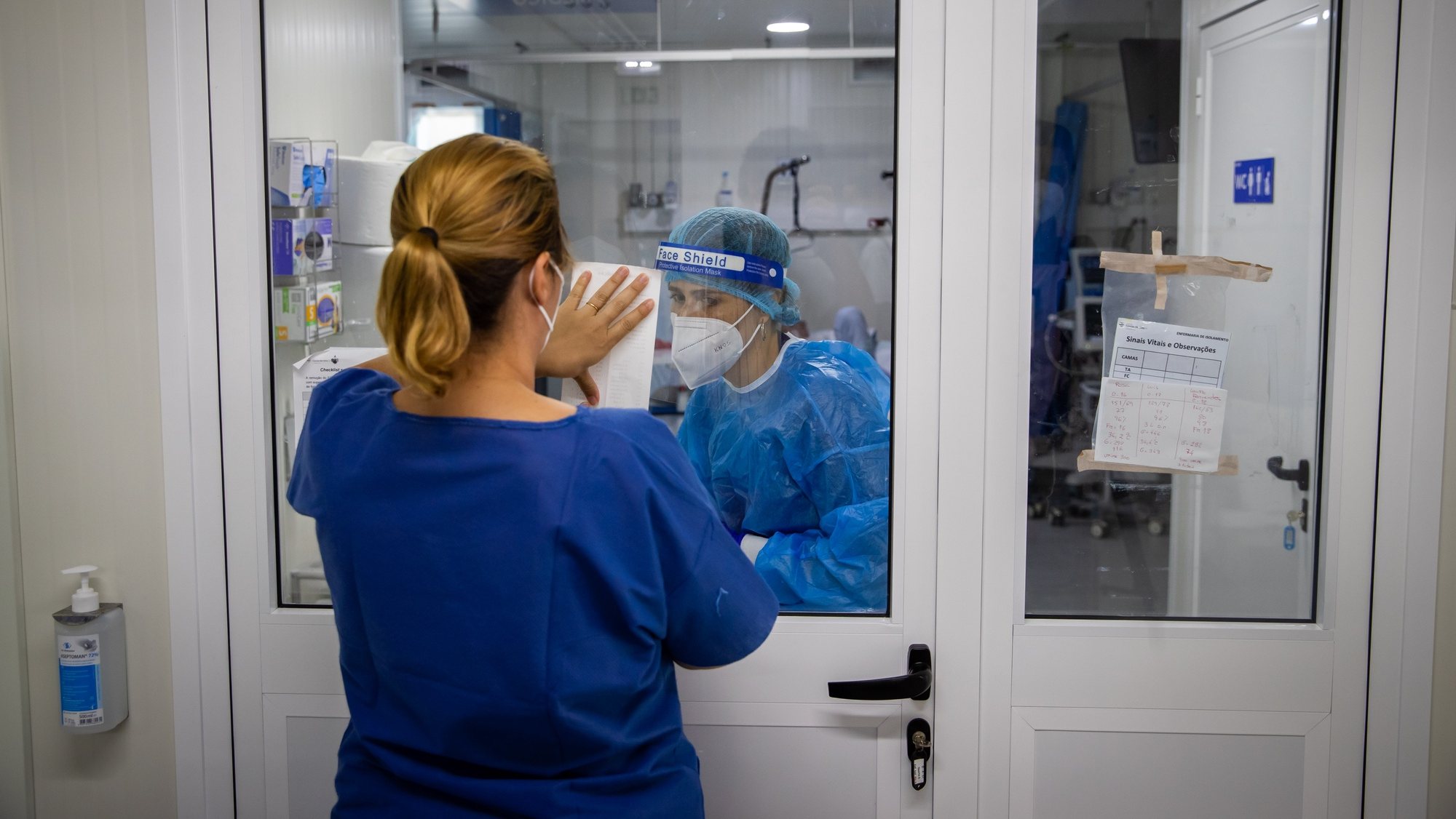Uma enfermeira mostra indicações numa folha a uma médica dentro de um quarto de pacientes em isolamento devido à Covid-19, na Enfermaria de isolamento do Hospital Garcia de Orta, em Almada, 21 de julho de 2021. JOSÉ SENA GOULÃO/LUSA (ACOMPANHA TEXTO DE 24/07/2021)