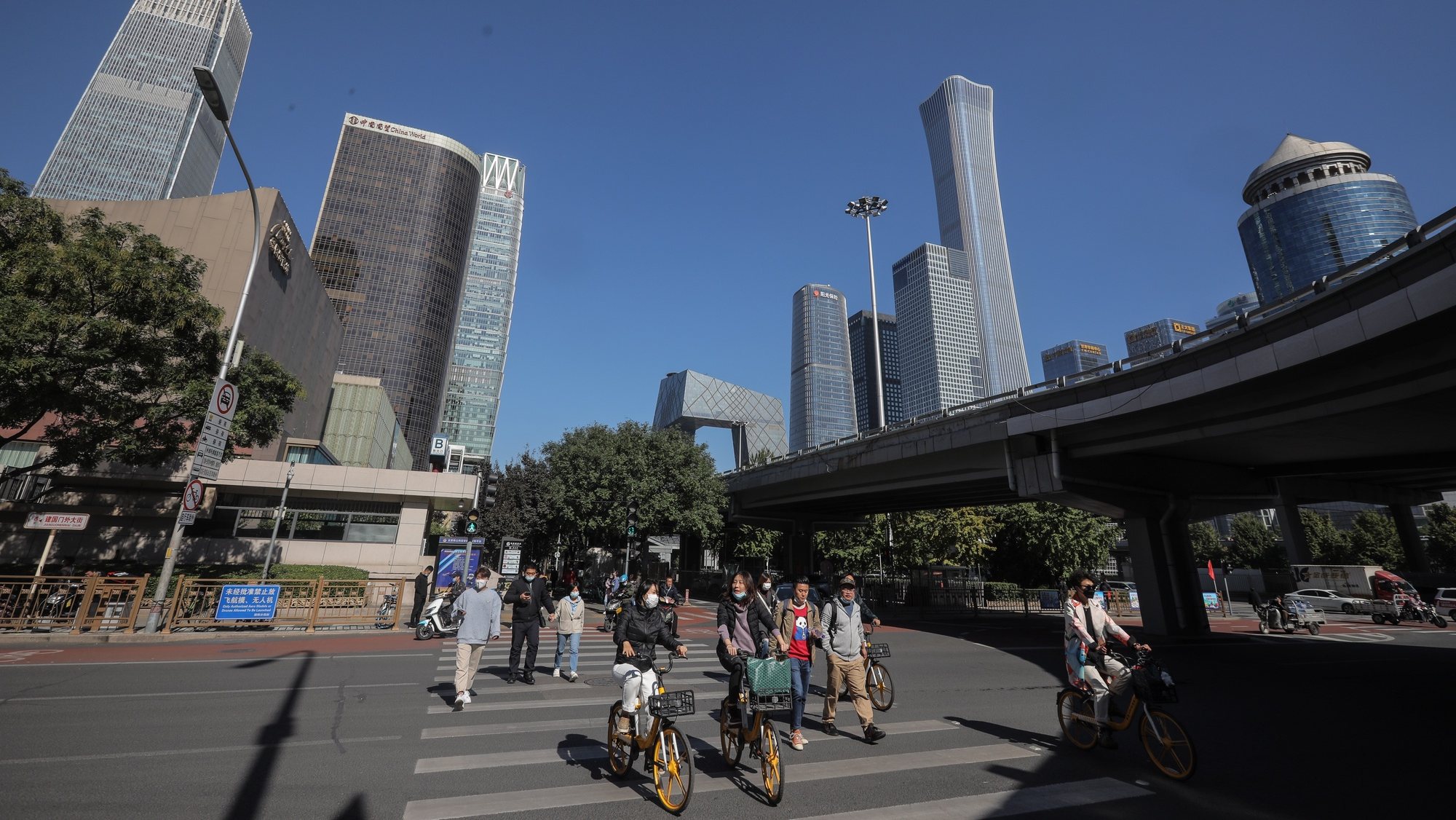 epa09529483 People walk and ride bicycles in the central business district (CBD) in Beijing, China, 17 October 2021 (issued 18 October 2021). China&#039;s gross domestic product (GDP) rose 4.9 percent year on year in the third quarter of 2021, according to data from the National Bureau of Statistics (NBS) issued on 18 October 2021.  EPA/WU HONG