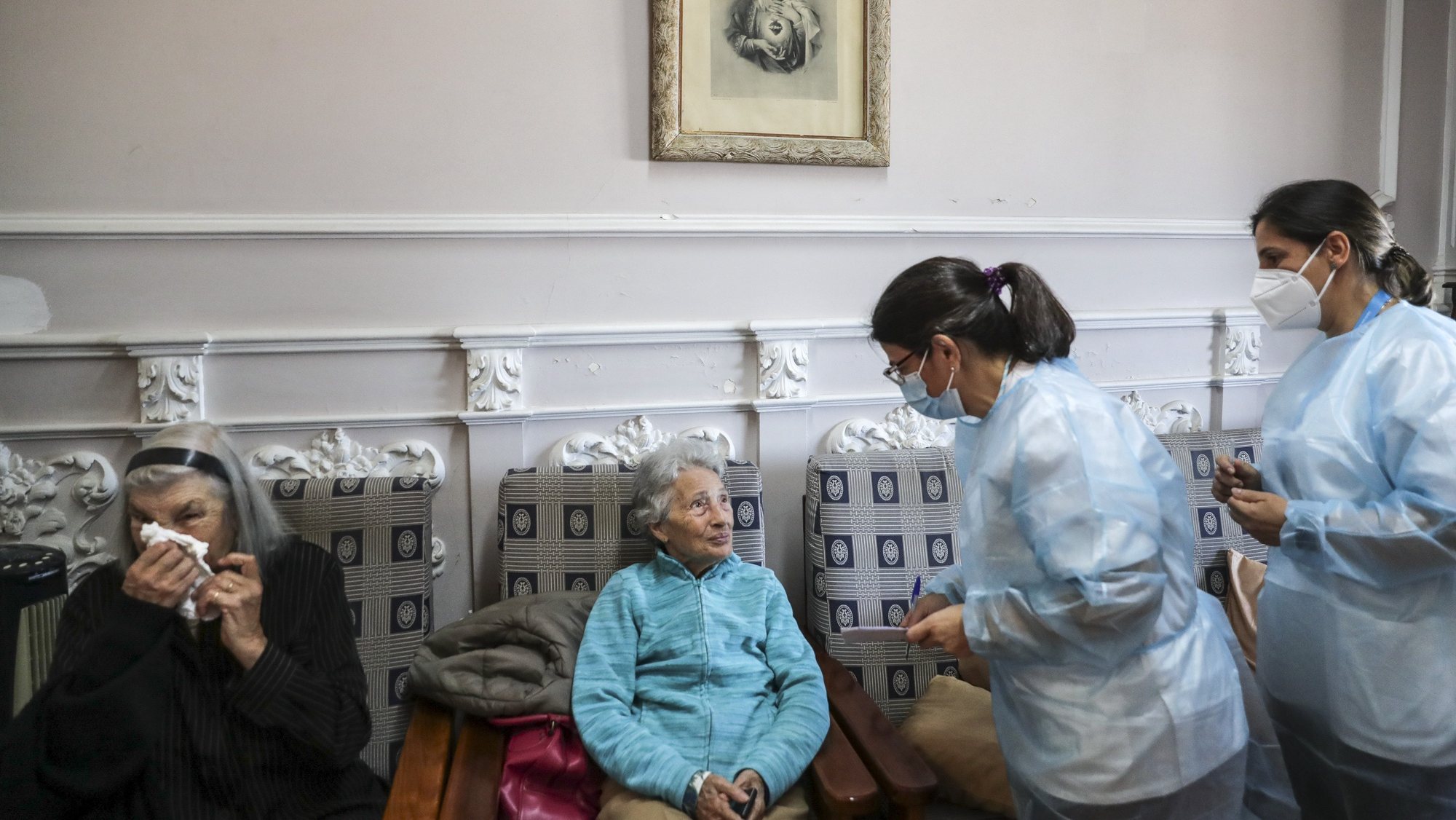 Uma utente de um lar de terceira idade conversa com enfermeiras momentos antes de ser vacinada com a quinta dose da vacina contra a covid-19, em Lisboa, 19 de maio de 2022. TIAGO PETINGA/LUSA