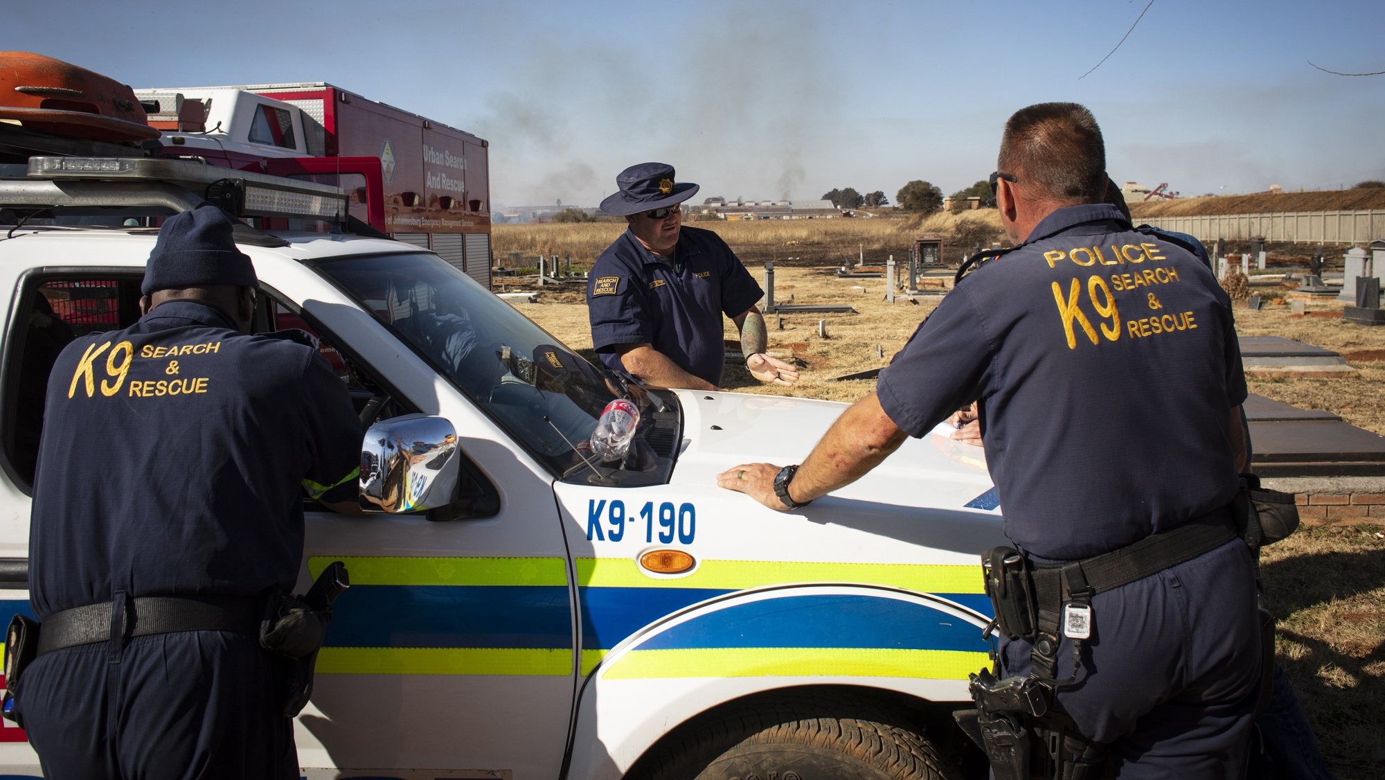 epa10018126 Members of the SAPS (South African Police Force) K9 unit discuss their approach during the ongoing search operation for a boy, Khayalethu Magadla (6), who fell into a water pipe six days ago, Soweto, Johannesburg , South Africa, 17 June 2022. Johannesburg EMS and SAPS police unites are continuing their search with robots being used in the underground waterways near where the boy went missing.  EPA/KIM LUDBROOK
