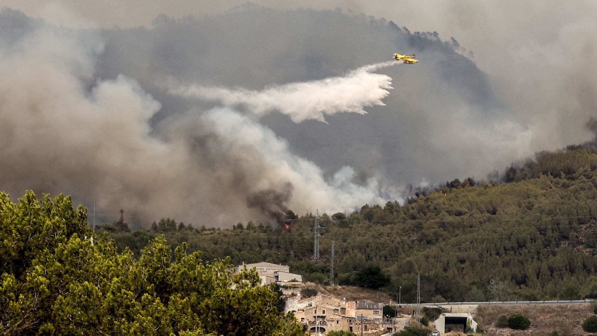 epa10076248 A firefighting aircraft drops water on a forest fire originated in Pont de Vilomara, Spain, 17 July 2022. The fire has burnt 440 hectares so far.  EPA/TONI ALBIR