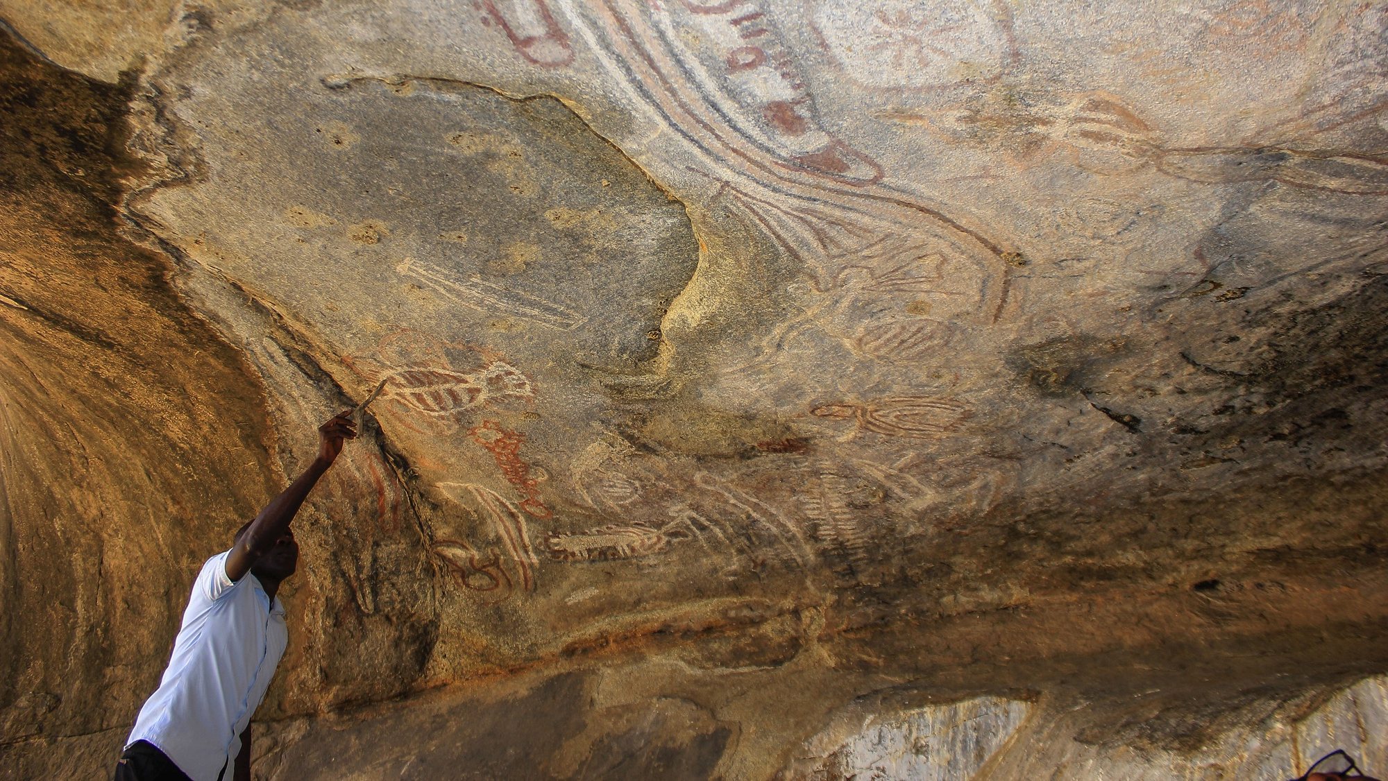 Paihama Catenga, responsável da área de cultura e turismo da Administração Municipal do Virei, mostra uma das pinturas rupestres de Tchitundo-Hulo, discretamente desenhadas em grutas remotas do sul de Angola, estão entre os vestígios arqueológicos mais importantes do país, mas a falta de proteção ameaça o valioso património, em Moçâmedes, município do Virei, província do Namibe, Angola, 16 de novembro de 2022. Diz-se que “caíram do céu” - o significado de Tchitundo-Hulo na língua local - e encontram-se a cerca de 130 quilómetros da sede do município do Virei, província do Namibe, numa região desértica à qual se acede seguindo uma picada arenosa. (ACOMPANHA TEXTO DA LUSA DO DIA 04 DE DEZEMBRO DE 2022). AMPE ROGÉRIO/LUSA