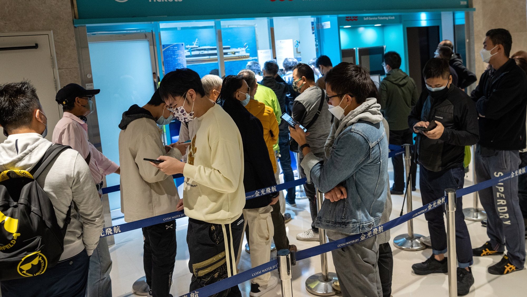 epa10391669 People line up to buy ferry tickets to  mainland China and Macau at the Hong Kong Macau Ferry Terminal in Hong Kong, China, 06 January 2023. On 08 January 2023 Hong Kong will reopen its borders with China and Macau allowing up to 60,000 Hong Kong travelers to enter mainland China and the Special Administrative Region of Macau on a daily basis, as China will scrap most of its Covid-19 travel restrictions and reopen to the world after almost three years.  EPA/JEROME FAVRE