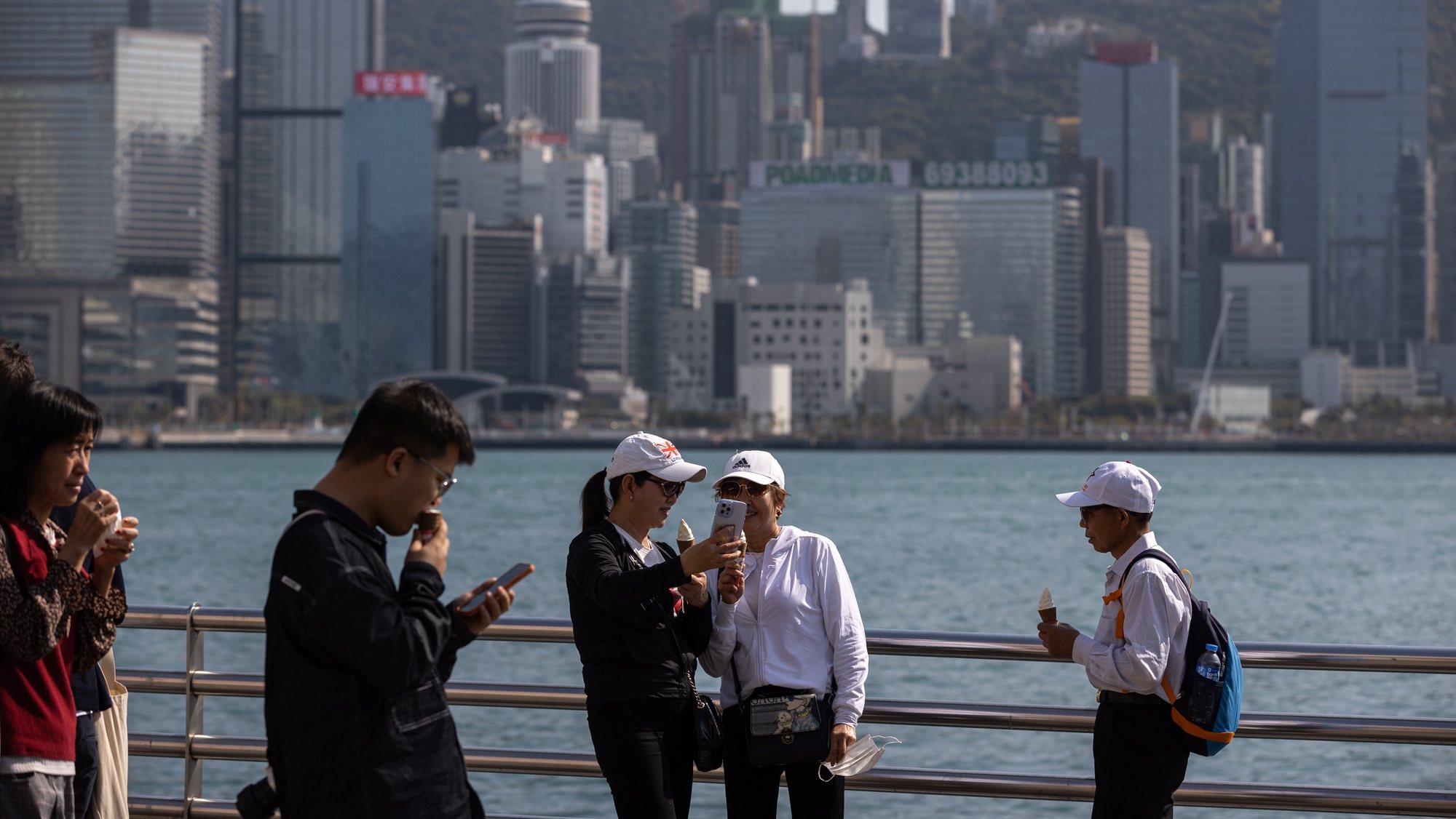 epa10505918 Mainland Chinese visitors take selfies on the Victoria Harbour waterfront in Hong Kong, China, 06 March 2023. More than 1.1 million mainland Chinese visitors arrived in Hong Kong in February 2023, a sharp increase from the 280,525 mainland visitors recorded in January 2023, according to the Hong Kong Tourism Board.  EPA/JEROME FAVRE