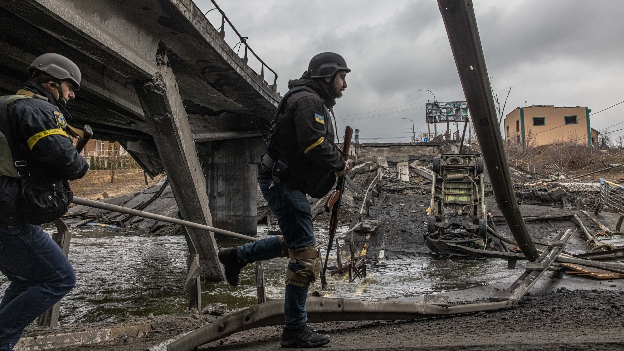 epa09799527 Ukrainian military members walk on a bridge destroyed by shelling in Irpin city, Kyiv (Kiev) province, Ukraine, 03 March 2022. Russian troops entered Ukraine on 24 February prompting the country&#039;s president to declare martial law and triggering a series of severe economic sanctions imposed by Western countries on Russia.  EPA/ROMAN PILIPEY