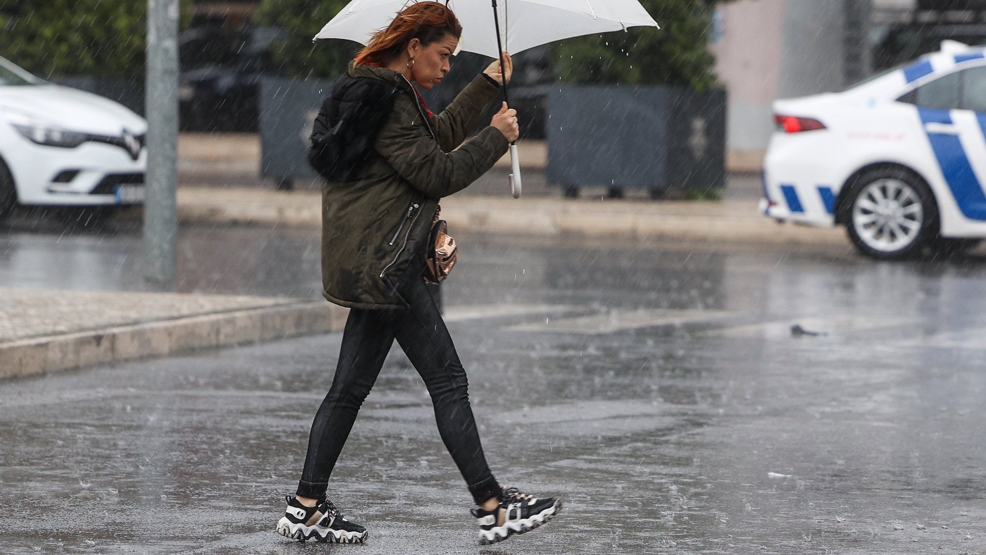 Uma traseunte passa com chapéu de chuva na zona de Algés em Oeiras num dia de temporal, 14 de dezembro de 2022. TIAGO PETINGA/LUSA