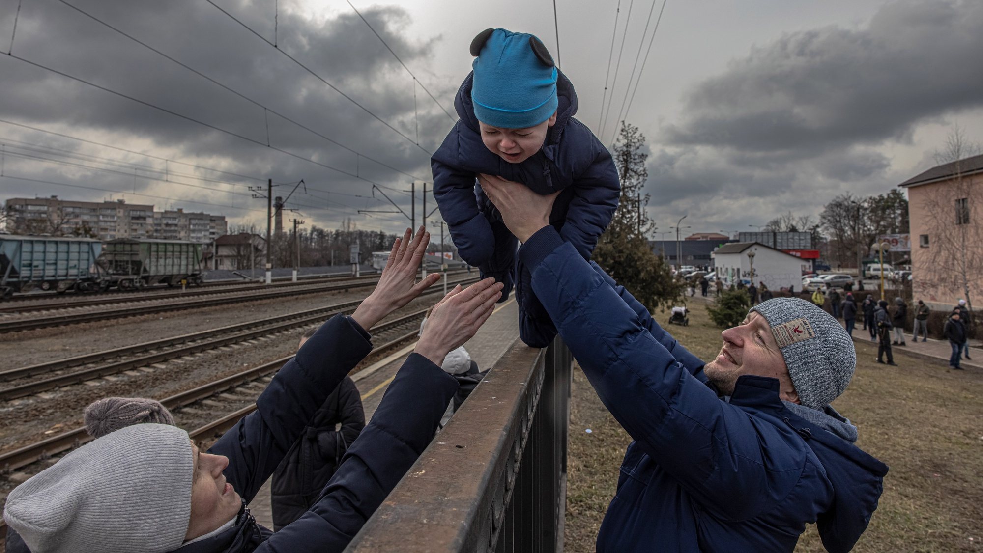 epa10364873 Oleg (R), who decided to stay in Irpin, passes his son Maksim over a fence to his wife, Yana, before the arrival of an evacuation train to the city of Kiev (Kyiv), at the train station in Irpin, Ukraine, 04 March 2022. People, mostly women and children, fled the frontline towns of Bucha and Irpin after heavy fighting broke out between Ukrainian and Russian forces in recent days.  EPA/ROMAN PILIPEY