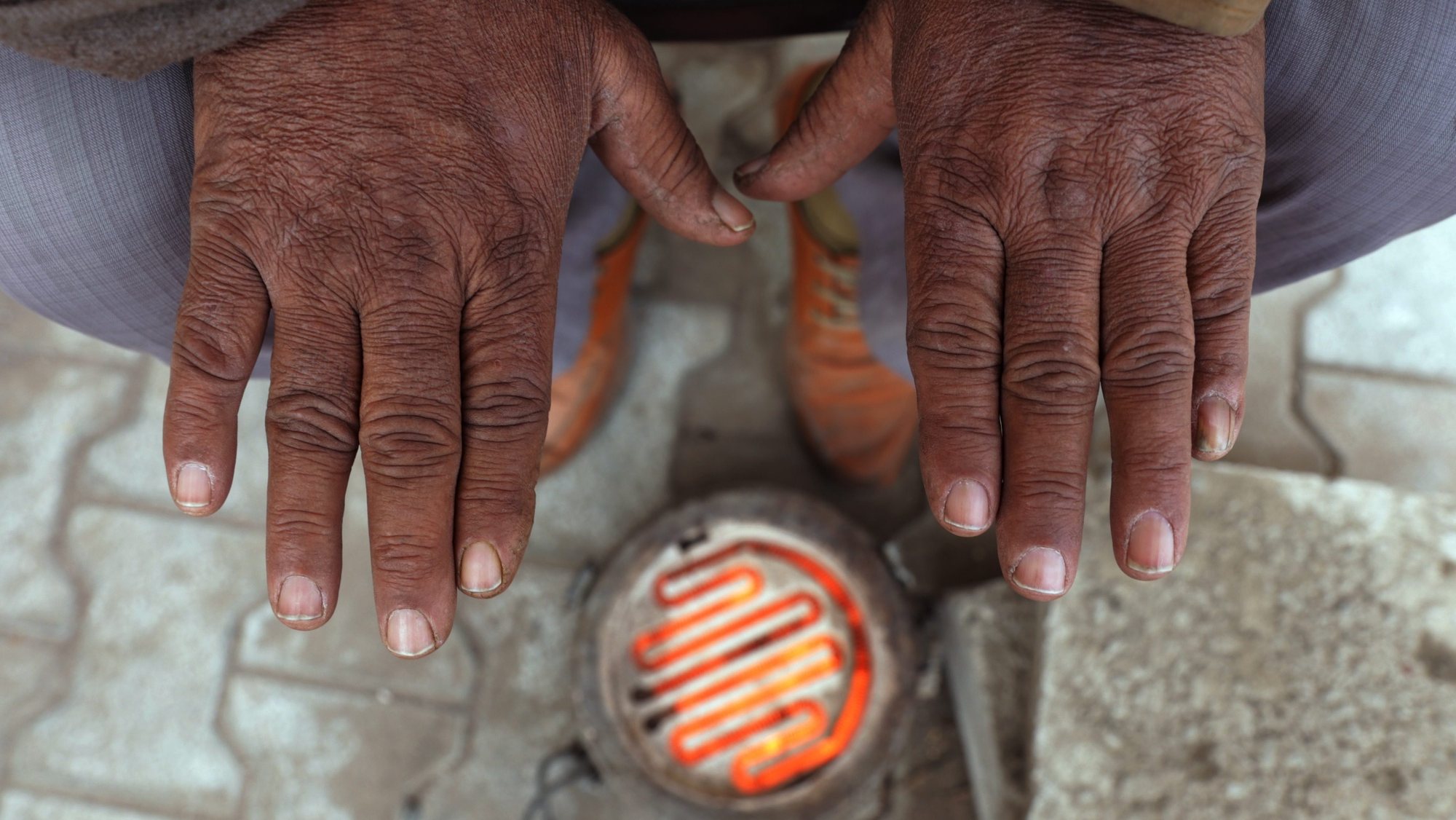 epa05661807 An Indian man warms his hands up over an electric heater on a cold and foggy morning in Amritsar, India, 06 December 2016. The region witnessed dense morning fog as winter season approaches its peak.  EPA/RAMINDER PAL SINGH