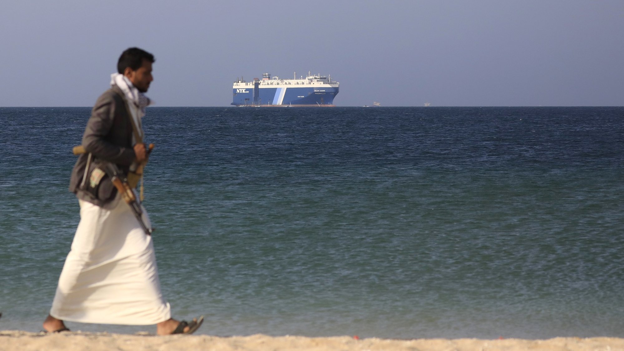 epaselect epa11014295 An armed Houthi fighter walks through the beach with the Galaxy Leader cargo ship in the background, seized by the Houthis offshore of the Al-Salif port on the Red Sea in the province of Hodeidah, Yemen, 05 December 2023 (issued 06 December 2023). Yemen&#039;s Houthis on 06 December 2023 claimed responsibility for the launch of the barrage of ballistic missiles toward Israel in support of the Palestinian people in the Gaza Strip, according to a statement by Houthis spokesman Yahya Saree. The Houthis vowed to continue their efforts to prevent Israeli ships from navigating in the Arabian and Red Seas, in retaliation for Israel&#039;s airstrikes on the Gaza Strip. Thousands of Israelis and Palestinians have died since the militant group Hamas launched an unprecedented attack on Israel from the Gaza Strip on 07 October, and the Israeli strikes on the Palestinian enclave which followed it.  EPA/YAHYA ARHAB