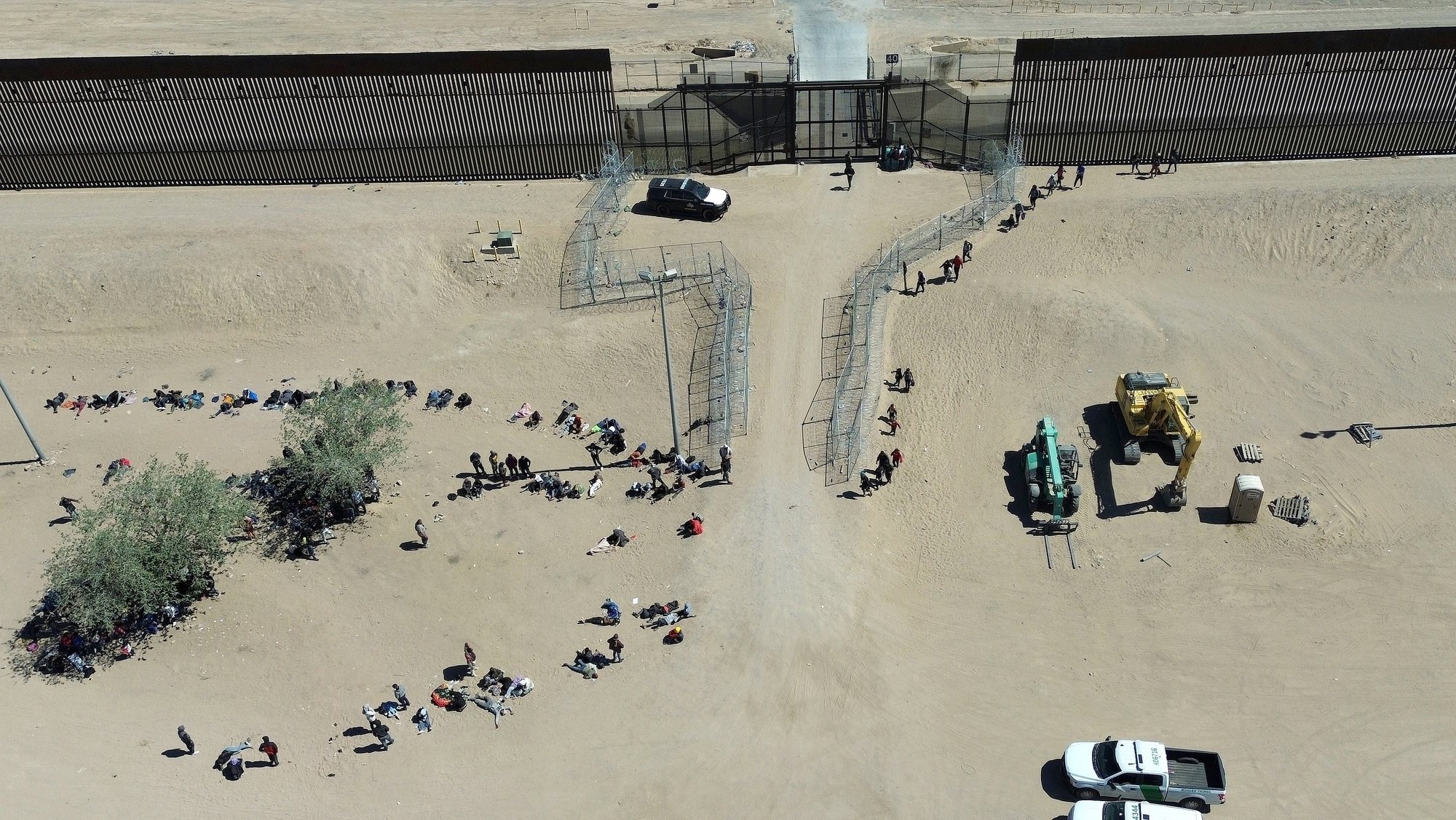 epa11287651 An aerial picture shows migrants on the border with the United States, in Ciudad Juarez, Mexico, 18 April 2024. About 400 migrants managed to force their way to the wall between Juarez and El Paso on 18 April after crossing the razor wire fence and overcoming a group of National Guard agents, and then being processed by the United States Immigration Department.  EPA/Luis Torres
