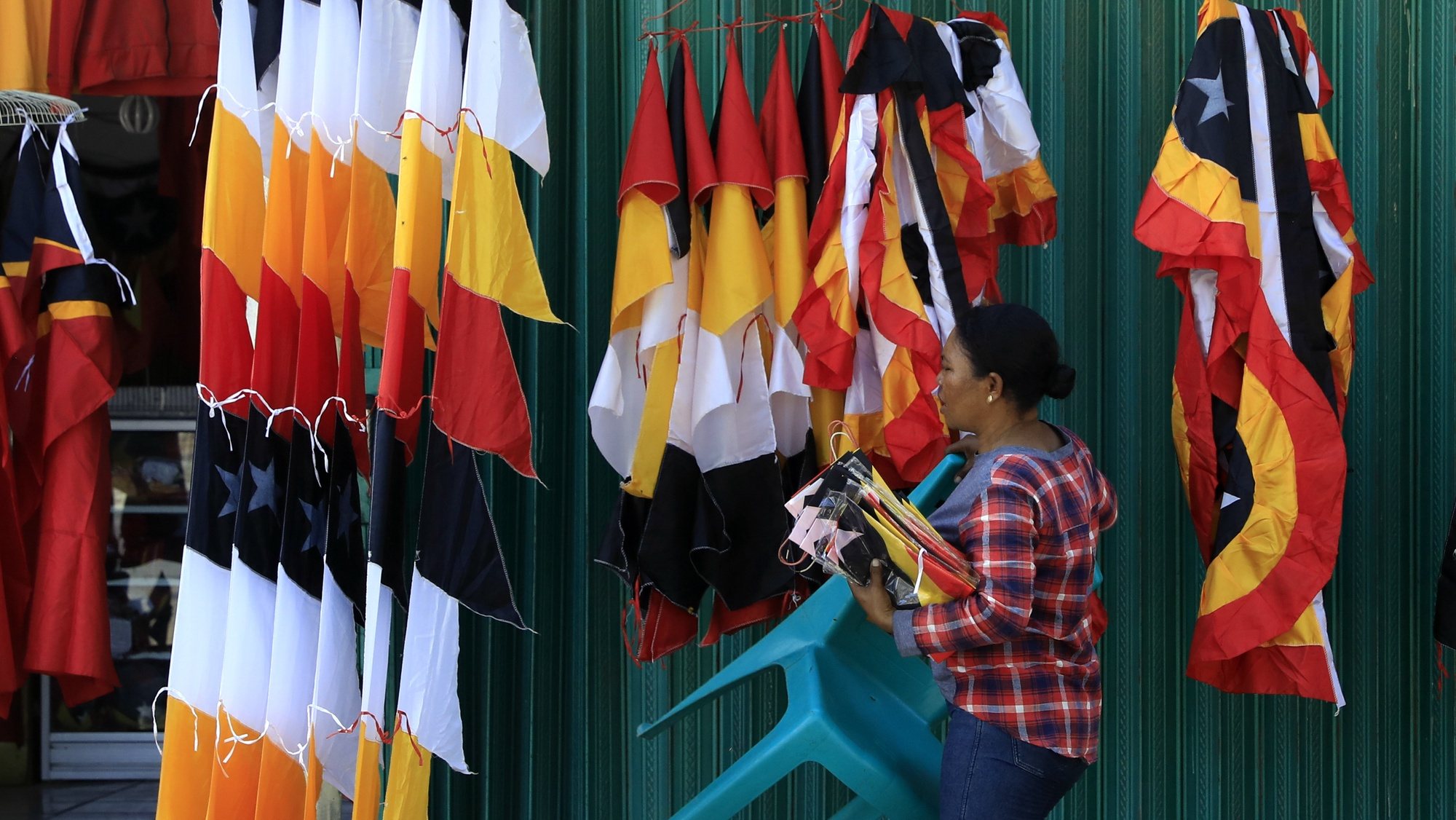 epa08842968 A vendor arranges flags as she waits for customers on the street side in Dili, East Timor, also known as Timor Leste, 26 November 2020.  EPA/ANTONIO DASIPARU