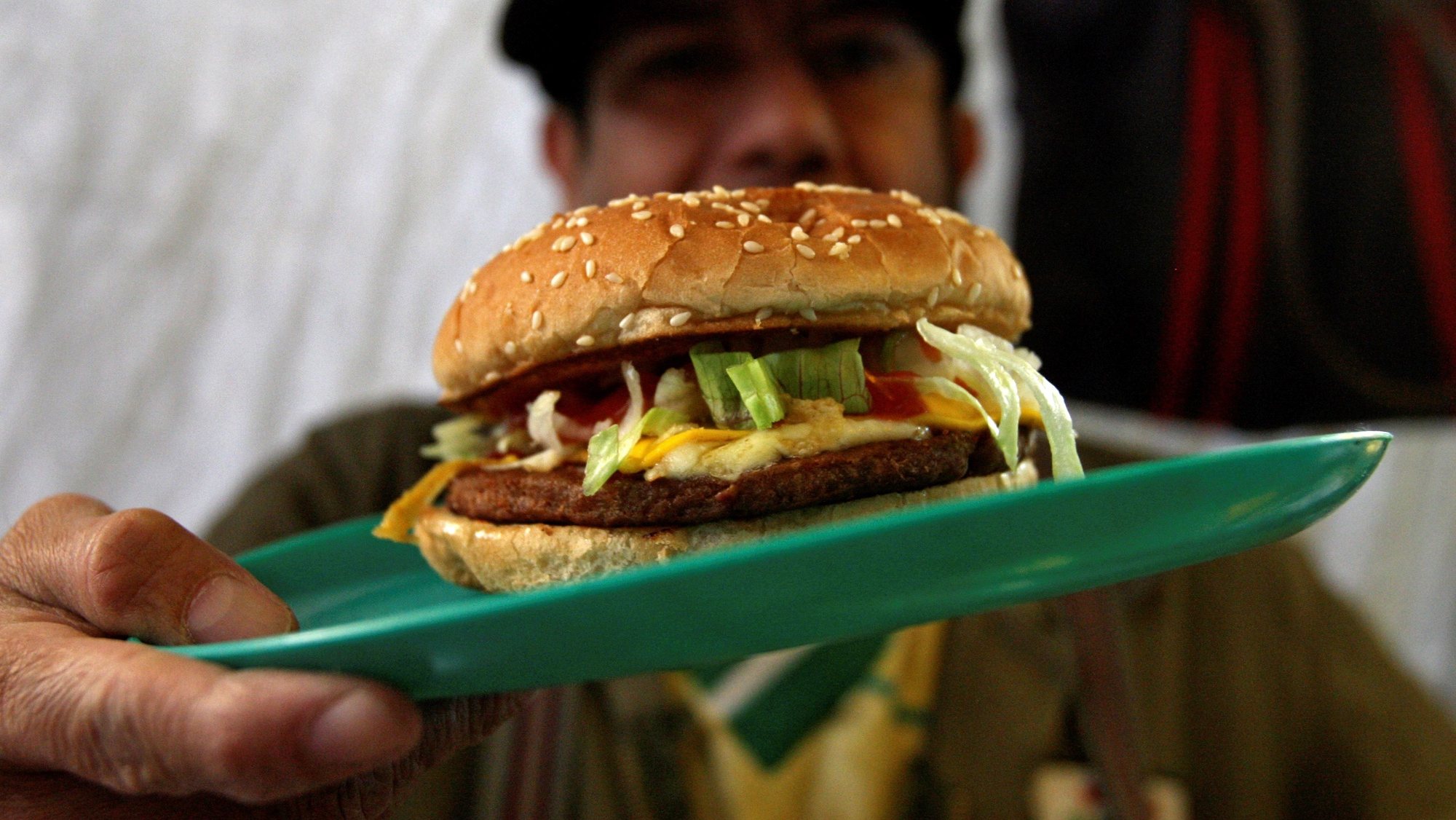 epa07924869 A Mexican man shows a cheeseburger in Mexico City, Mexico, 16 October 2019. According to the Food and Agriculture Organization (FAO), obesity affects almost 2,000 million people. In Latin America and the Caribbean have 105 million adults with obesity and 42 million starving representing a global tendency; there is more obese than people starving. Junk food is the clue for these figures. Non-processed food such as vegetables, meat, fish or cereals are more expensive than ultra-processed food, not only in the First World but also in the Third World. EFE/ Mario Guzman  EPA/Mario Guzman