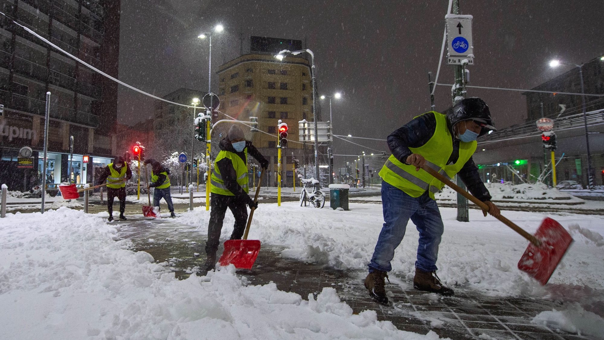 epa08907558 City workers clear the road from the snow at viale Gorizia during snowfall in Milan, northern Italy, 28 December 2020. Snowfall affected several regions of northern Italy causing some traffic disruption on motorways.  EPA/ANDREA FASANI