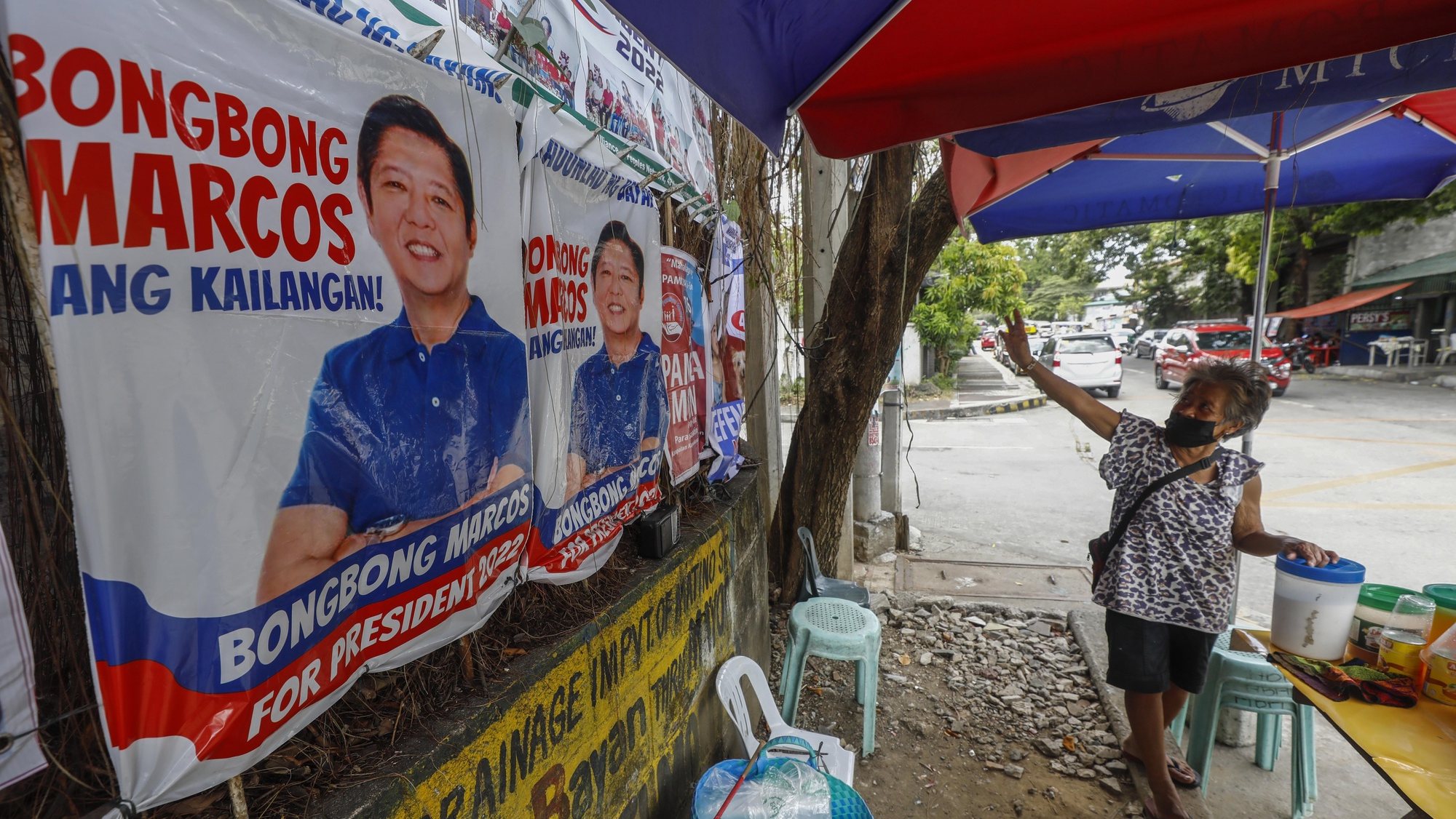 epa09873156 A sidewalk vendor of refreshments points to campaign posters of presidential candidate Ferdinand &#039;Bongbong&#039; Marcos Jr., son of the late president Ferdinand Marcos, in Quezon City, Metro Manila, Philippines 31 March 2022 (issued 06 April 2022). Activists have voiced concern over the possible return of &#039;a powerful dynasty&#039; to the head of state and Martial Law era human rights abuses as Ferdinand &#039;Bongbong&#039; Marcos Jr., son of the late dictator Ferdinand Marcos, lead the polls in the run for the presidency in the 09 May 2022 elections. According to Amnesty International, 3,257 people were made victims of extrajudicial killings and 35,000 were tortured during the Martial Law years from 1972 to 1986. The Philippine presidential and vice-presidential elections are scheduled to be held on 09 May 2022.  EPA/ROLEX DELA PENA  ATTENTION: This Image is part of a PHOTO SET