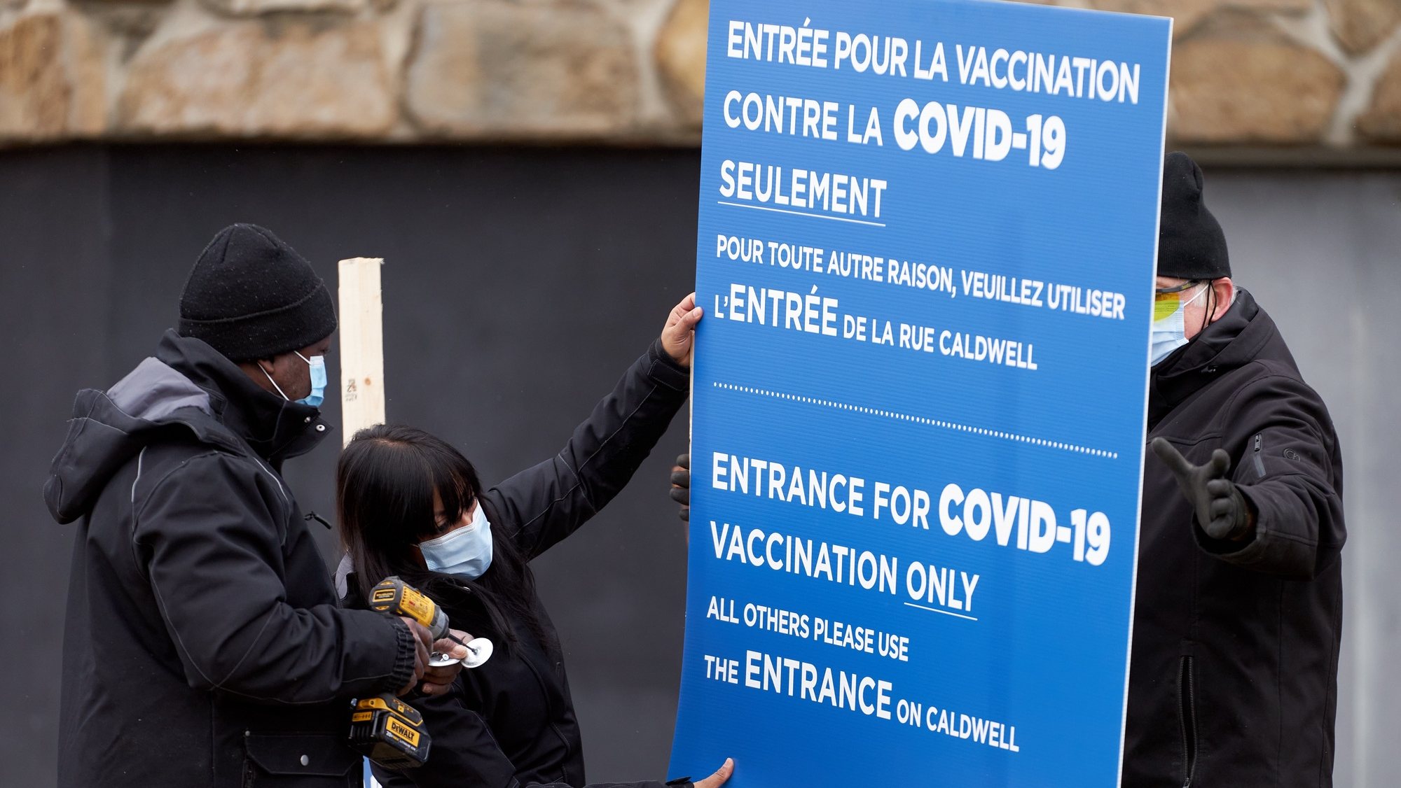 epa08883861 Workers set up signs at the first center to recive Covid-19 vaccine in Montreal, Canada, 14 December 2020. The first patients in Canada will be vaccinated there with the Pfizer BionNtech vaccine.  EPA/ANDRE PICHETTE