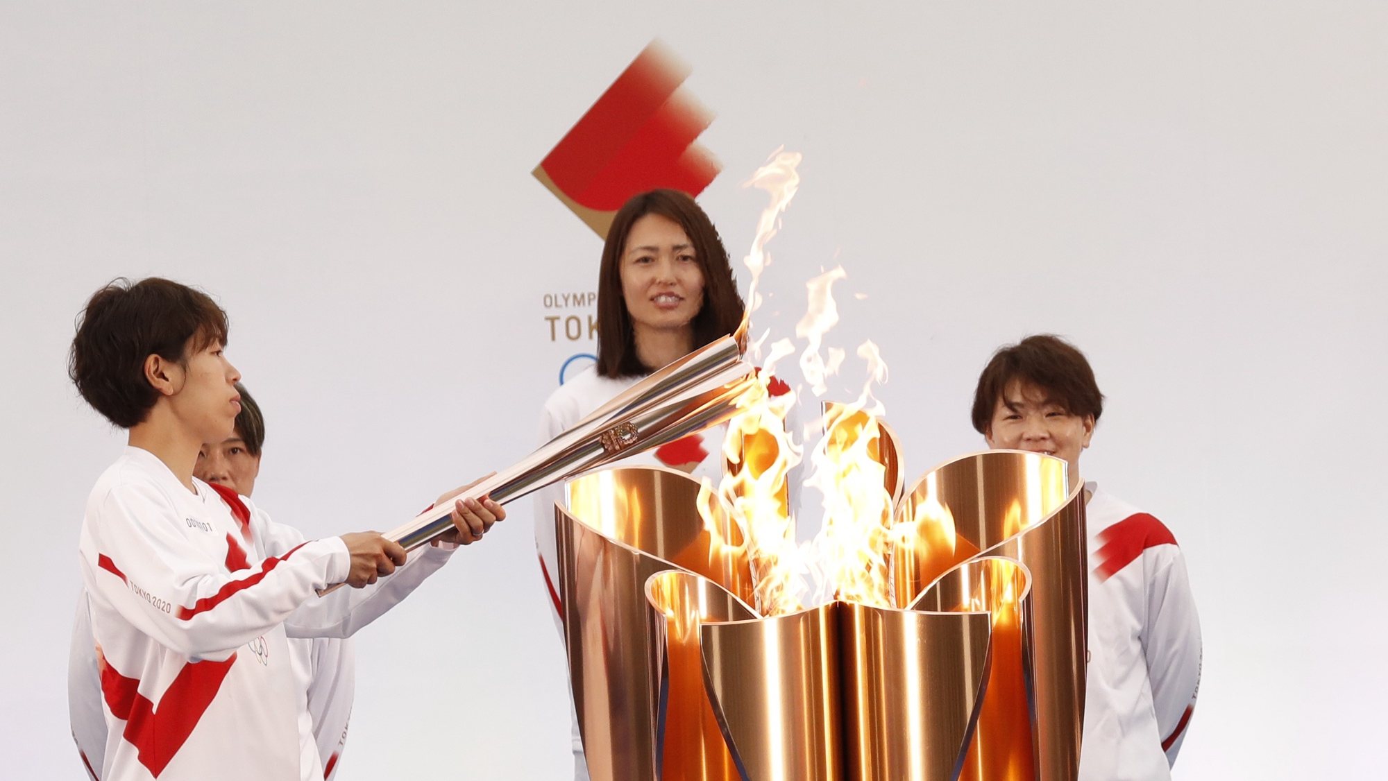 epa09095217 The Olympic torch is lit by a member of Japan&#039;s women&#039;s national soccer team Nadeshiko Japan during the Tokyo 2020 Olympic Torch Relay Grand Start in Naraha, Fukushima prefecture, Japan, 25 March 2021. The postponed Tokyo 2020 Olympic Games are scheduled to start on 23 July 2021 and some 10,000 torchbearers will run across the country along a 121-day journey.  EPA/KIM KYUNG-HOON / POOL