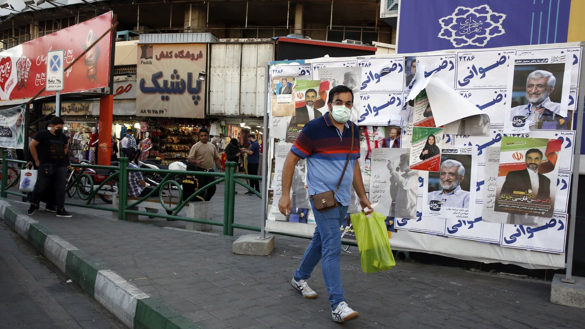 epa09274024 An Iranian man walks past elections billboard in a street in Tehran, Iran, 15 June 2021. Iranians will vote in a presidential election on 18 June 2021.   EPA/ABEDIN TAHERKENAREH