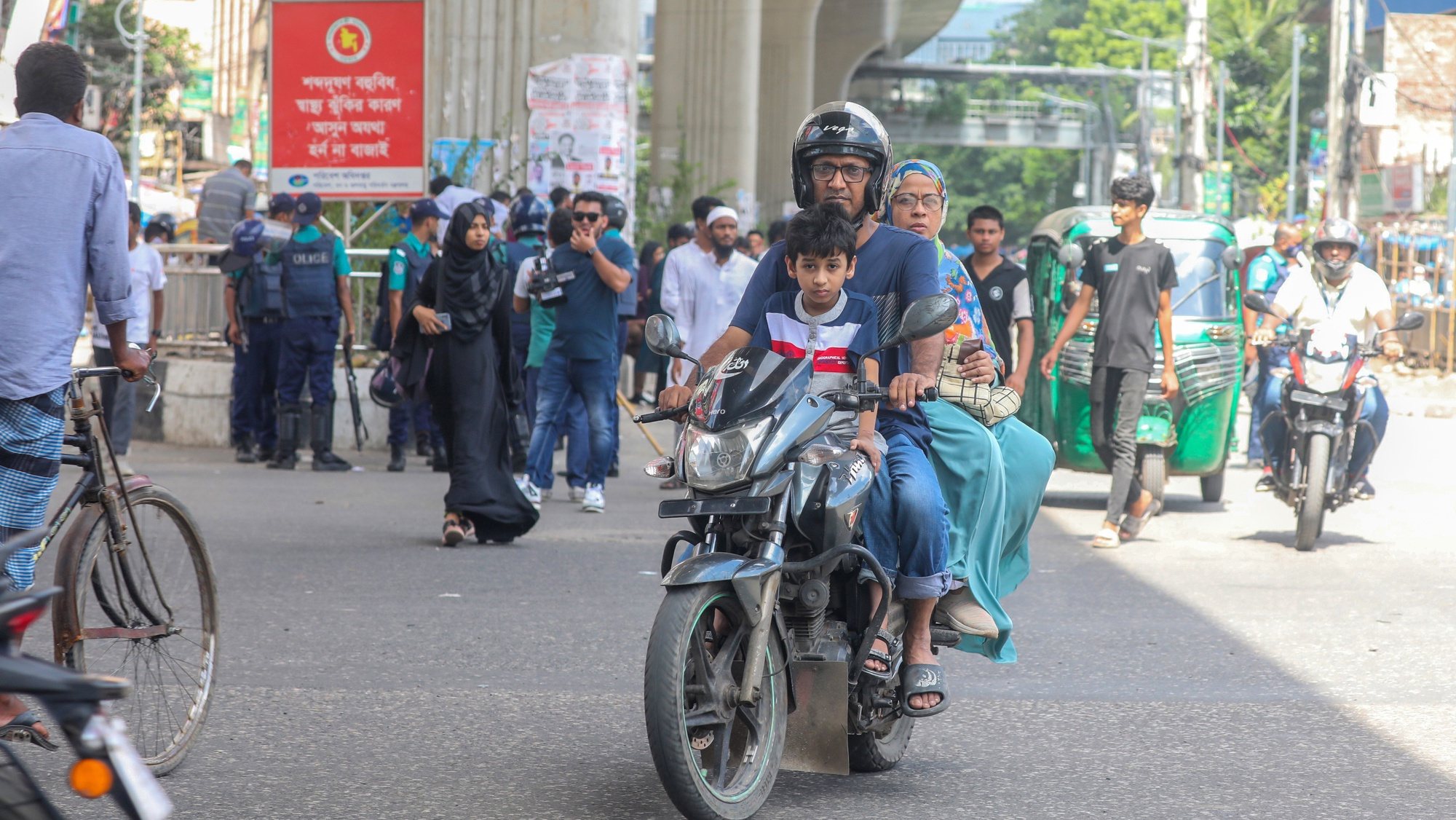epa11496945 A family ride a motorycle in Dhaka, Bangladesh, 26 July 2024, after a curfew was relaxed for a few hours. Authorities in Bangladesh have announced an easing of a curfew imposed after mass protests last week, allowing offices to open and some activity, and partially restoring telecommunication services. As casualties mounted and law enforcement struggled to contain the unrest, the Bangladeshi government had imposed a nationwide curfew and deployed military forces after violence broke out in Dhaka and other regions following student-led protests demanding reforms to the government&#039;s job quota system.  EPA/MONIRUL ALAM