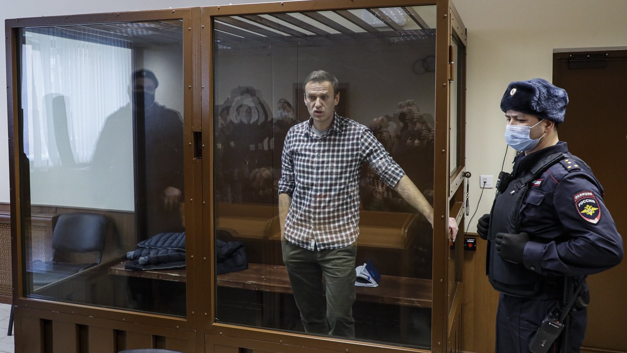 epa09025239 Russian opposition leader Alexei Navalny (C) stands inside a glass cage prior to a hearing at the Babushkinsky District Court in Moscow, Russia, 20 February 2021. The Moscow City court will hold a visiting session at the Babushkinsky District Court Building to consider Navalny&#039;s lawyers appeal against a court verdict issued on 02 February 2021, to replace the suspended sentence issued to Navalny in the Yves Rocher embezzlement case with an actual term in a penal colony.  EPA/YURI KOCHETKOV MANDATORY CREDIT