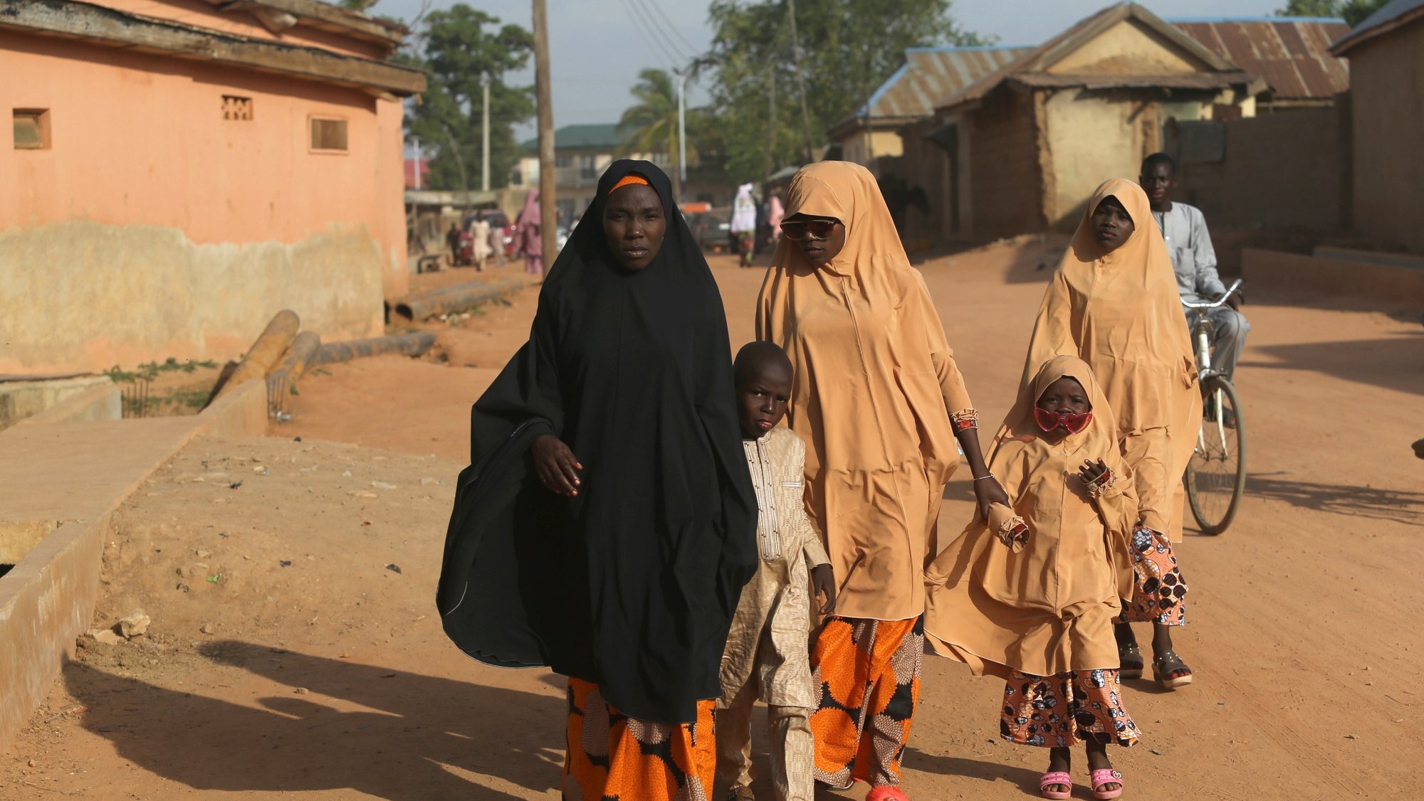 epa09200616 A Muslim woman walks along a road with her children after attending the Jumat prayer at the Zaria central mosque in northern Nigeria 14 May 2021. Muslims around the world are celebrating Eid al-Fitr, the three day festival marking the end of the Muslim holy fasting month of Ramadan. Eid al-Fitr is one of the two major holidays in Islam.  EPA/AKINTUNDE AKINLEYE