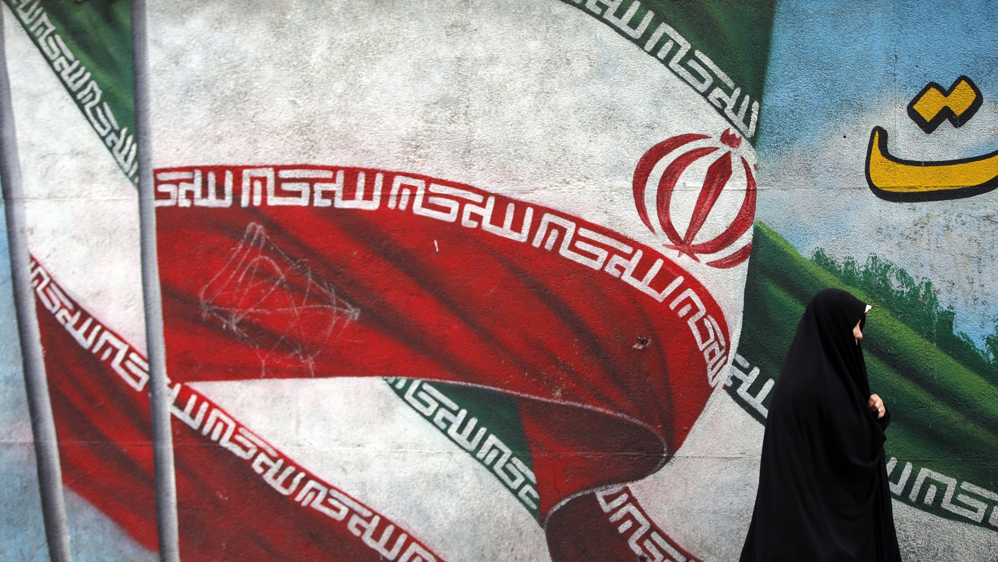 epaselect epa11314305 An Iranian woman walks past a painting of the national flag of Iran in Tehran, Iran, 02 May 2024. Iranians will vote on 10 May 2024 for the second round of Iranian parliamentary elections.  EPA/ABEDIN TAHERKENAREH