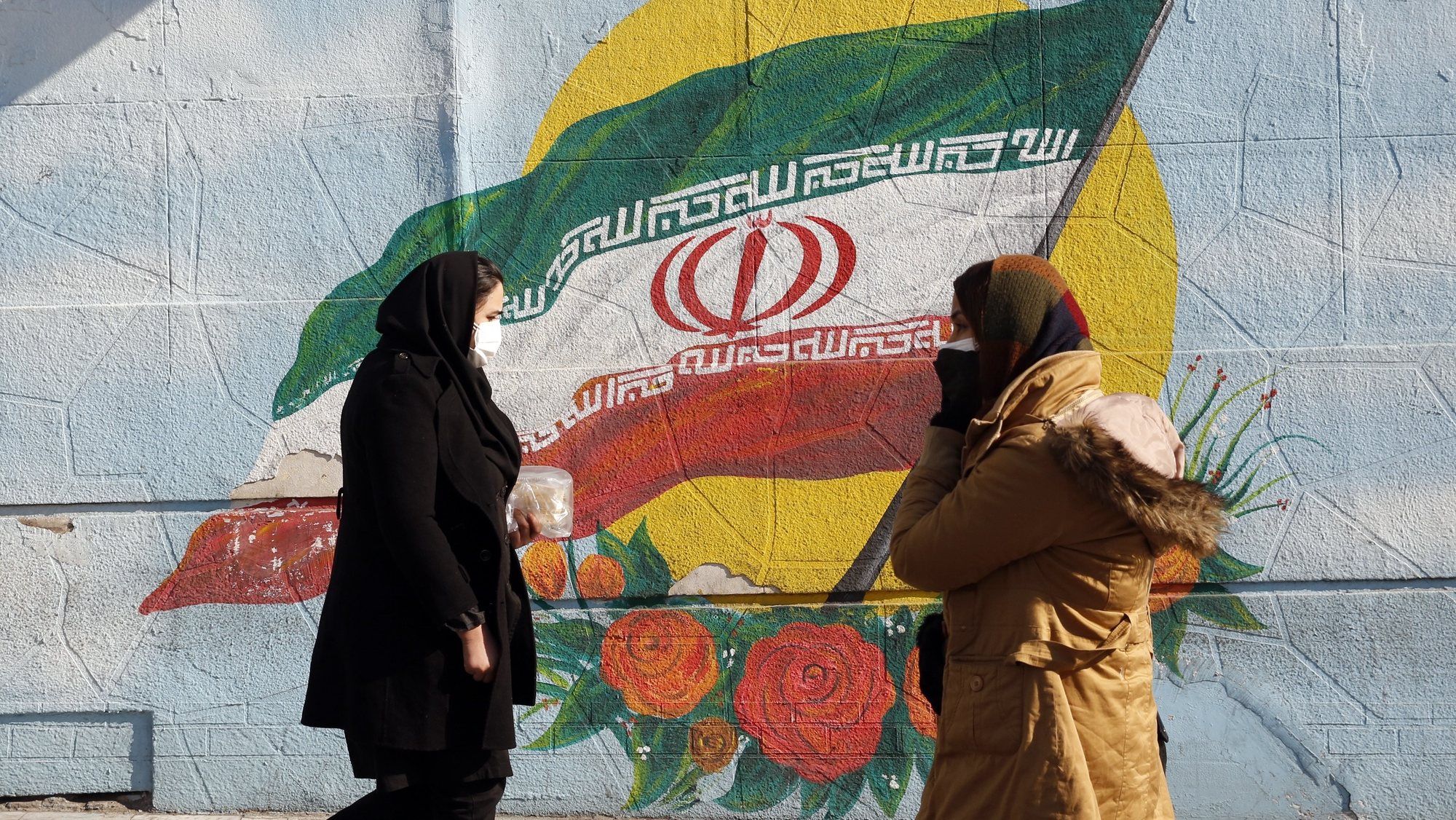 epa09701867 Iranians walk past next to a wall painting of Iran’s national flag in a street in Tehran, Iran, 22 January 2022. As nuclear talks between Iran and world powers is going on in Vienna, Austria, according to Tasnim news agency Iran denied on 22 January any interim agreement in Vienna as saying they are looking for durable and reliable agreement. Iranians hope that sanctions will be lifted as the country is facing high economic crisis over the sanctions by US and world over Iran&#039;s nuclear program.  EPA/ABEDIN TAHERKENAREH