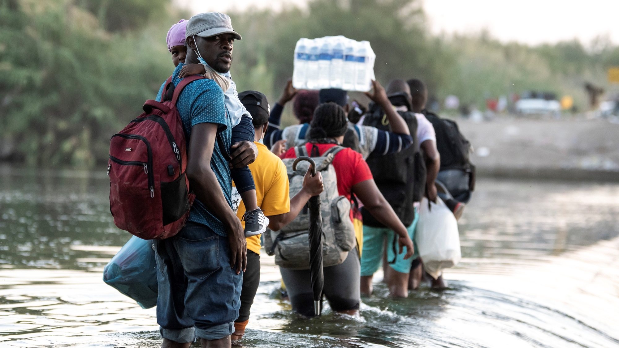 epa09475512 A group of Haitian migrants begin to cross the Rio Grande, on the border of Ciudad Acuna, Mexico, 18 September 2021. More than 10,000 migrants have arrived in the border cities of Del Rio Texas in the United States and Ciudad Acuna in Mexico in recent days and are waiting under the International Bridge for the asylum application to be processed by the United States authorities.  EPA/Miguel Sierra
