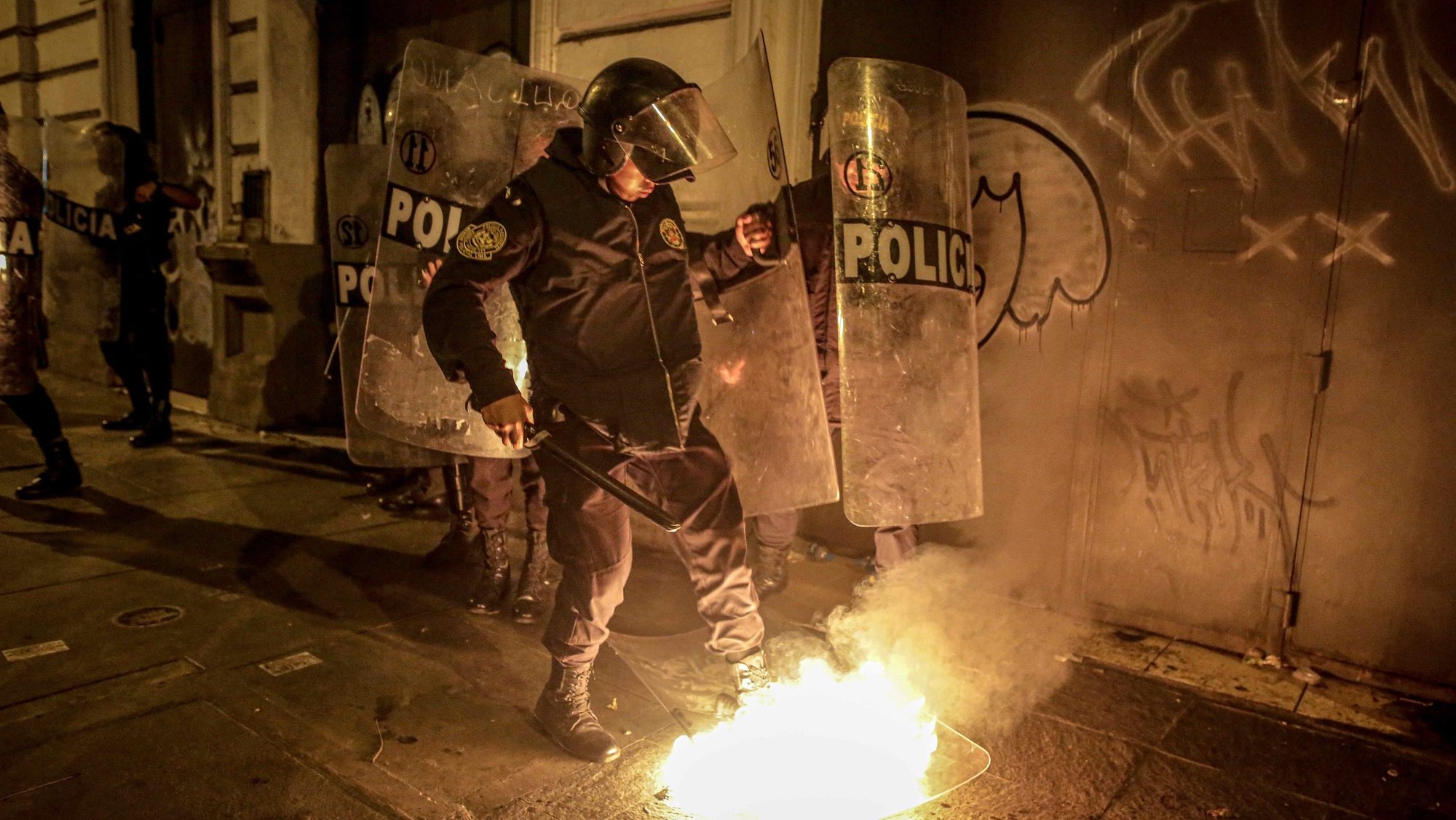 epaselect epa10458223 A policeman tries to put out a fire on a shield of the security forces, during an anti-government mobilization in the historic center of Lima, which brought together thousands of Peruvians who demanded the resignation of President Dina Boluarte, in Lima, Peru, 09 February 2023. The Peruvian National Police (PNP) deployed nearly 10,000 agents as the protest strike demanded the resignation of Boluarte, a transitional government with the election of new leadership in Congress, and a referendum for a new constitution to replace the current one, which was drawn up in 1993 under the government of former President Alberto Fujimori (1990-2000).  EPA/Stringer