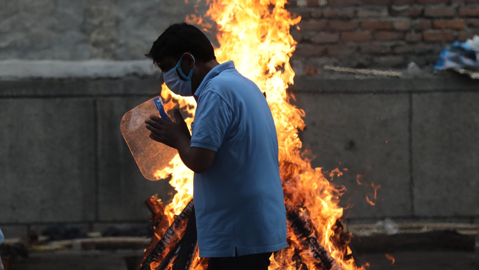 epa09209134 Relatives perform the last rites for a COVID-19 victim at a crematorium in New Delhi, India, 18 May 2021. India surpassed 25 million cases of the coronavirus on 18 May since the start of the pandemic, despite a decline in infections in recent days, while also recording a new daily record of 4,329 deaths. The country registered 263,533 infections in the last 24 hours, according to data from the Indian Ministry of Health, the lowest number in a month after India reported a record of over 400,000 cases everyday two weeks ago.  EPA/RAJAT GUPTA