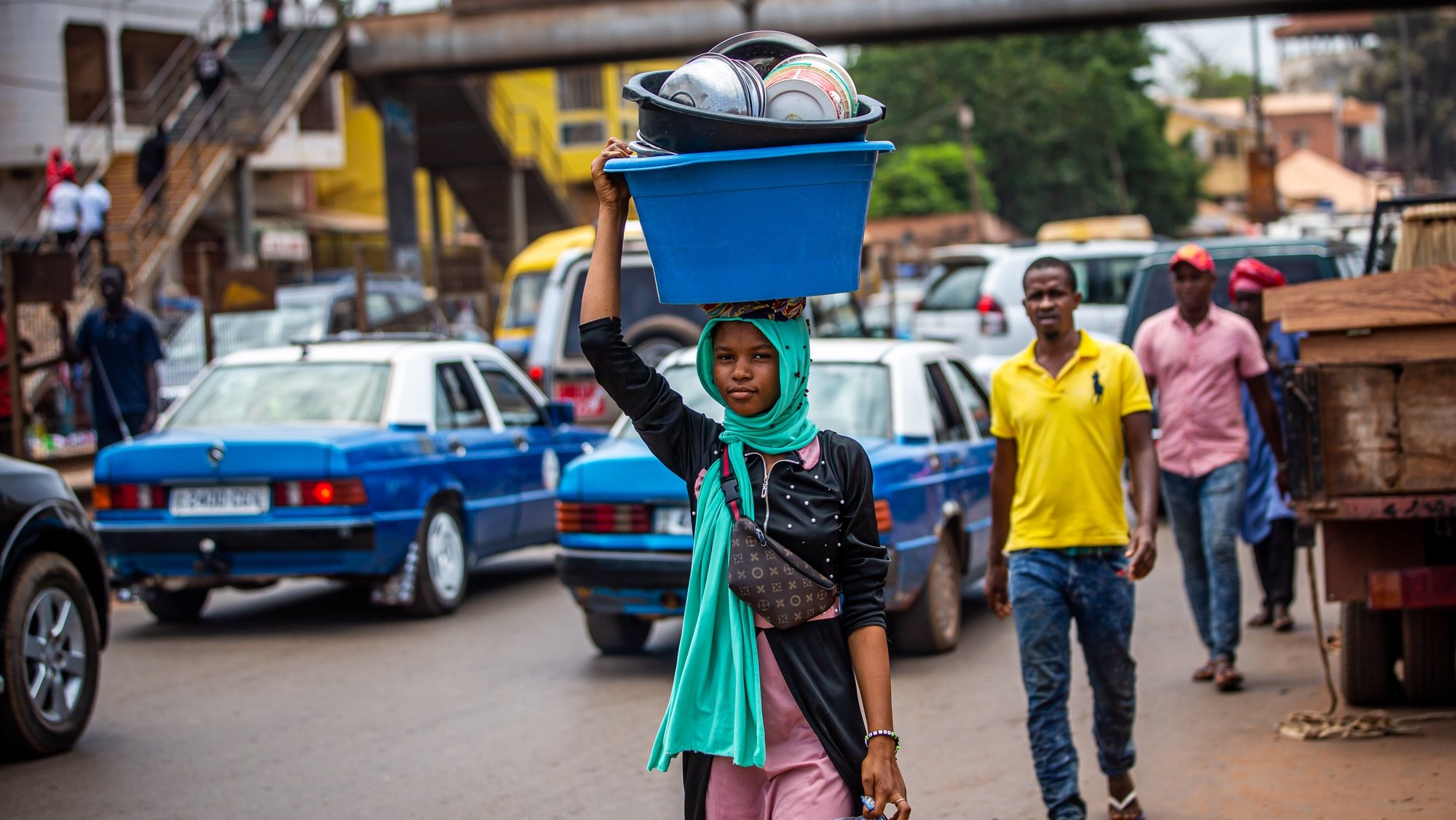 Uma mulher transporta objetos numa travessa na cabeça, junto ao Mercado Bandim, em Bissau, na Guiné-Bissau, 16 de maio de 2021. JOSÉ SENA GOULÃO/LUSA
