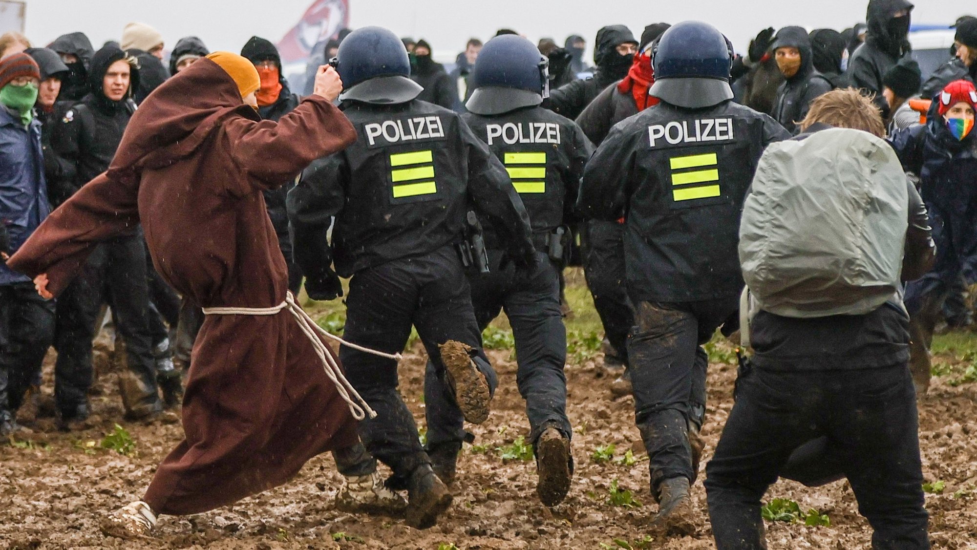 epa10405295 Police officers run during a rally of climate protection activists near the village of Luetzerath, Germany, 14 January 2023. Luetzerath in North Rhine-Westphalia state is to make way for lignite mining despite the decision to phase out coal. The Garzweiler open pit mine, operated by German energy supplier RWE, is the focus of protests by people who want Germany to stop mining and burning coal as soon as possible in the fight against climate change.  EPA/RONALD WITTEK