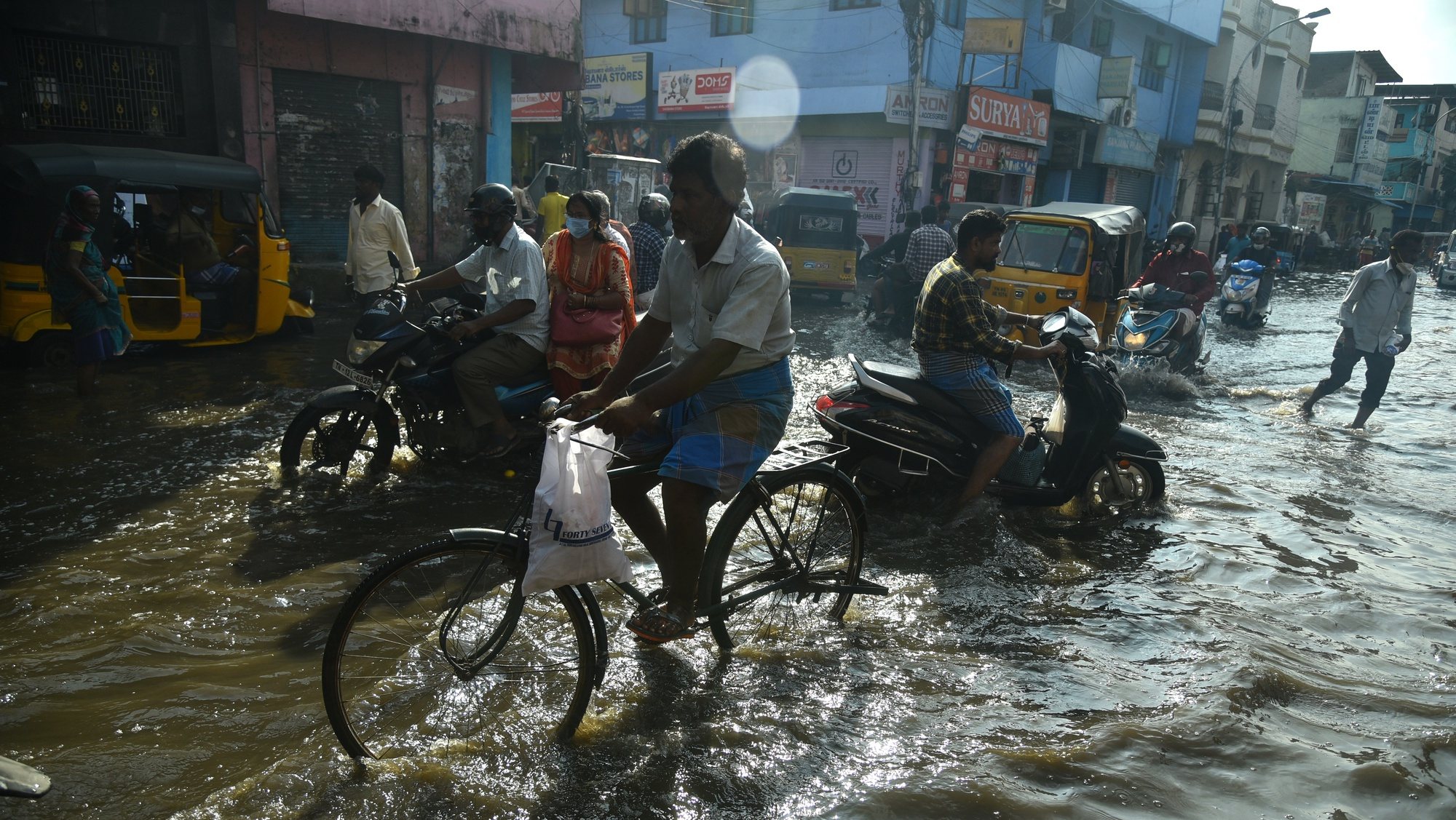 epa09581684 People commute through a waterlogged road following incessant heavy rains, in Chennai, India, 14 November 2021. The India Meteorological Department (IMD) has withdrawn a red alert for extremely heavy rainfall in Chennai and rainfall across the state of Tamil Nadu is likely to reduce from 15 November. While floodwater receded in the majority of the inundated areas, water stagnation persisted in a few areas of Chennai following heavy rains. Tamil Nadu reports 17 deaths due to heavy rains and waterlogging in several places.  EPA/IDREES MOHAMMED