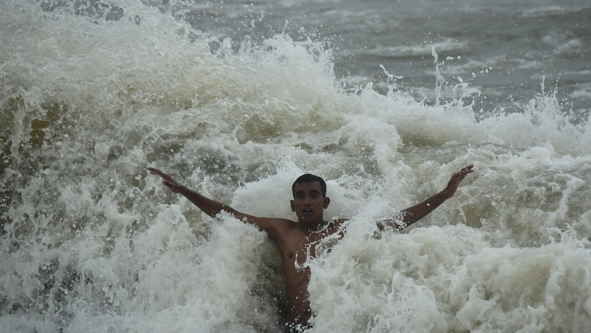 epa09356753 A youth gets splashed by a huge wave while swimming at Foreshore Estate beach in Chennai, India. 21 July 2021.  EPA/IDREES MOHAMMED