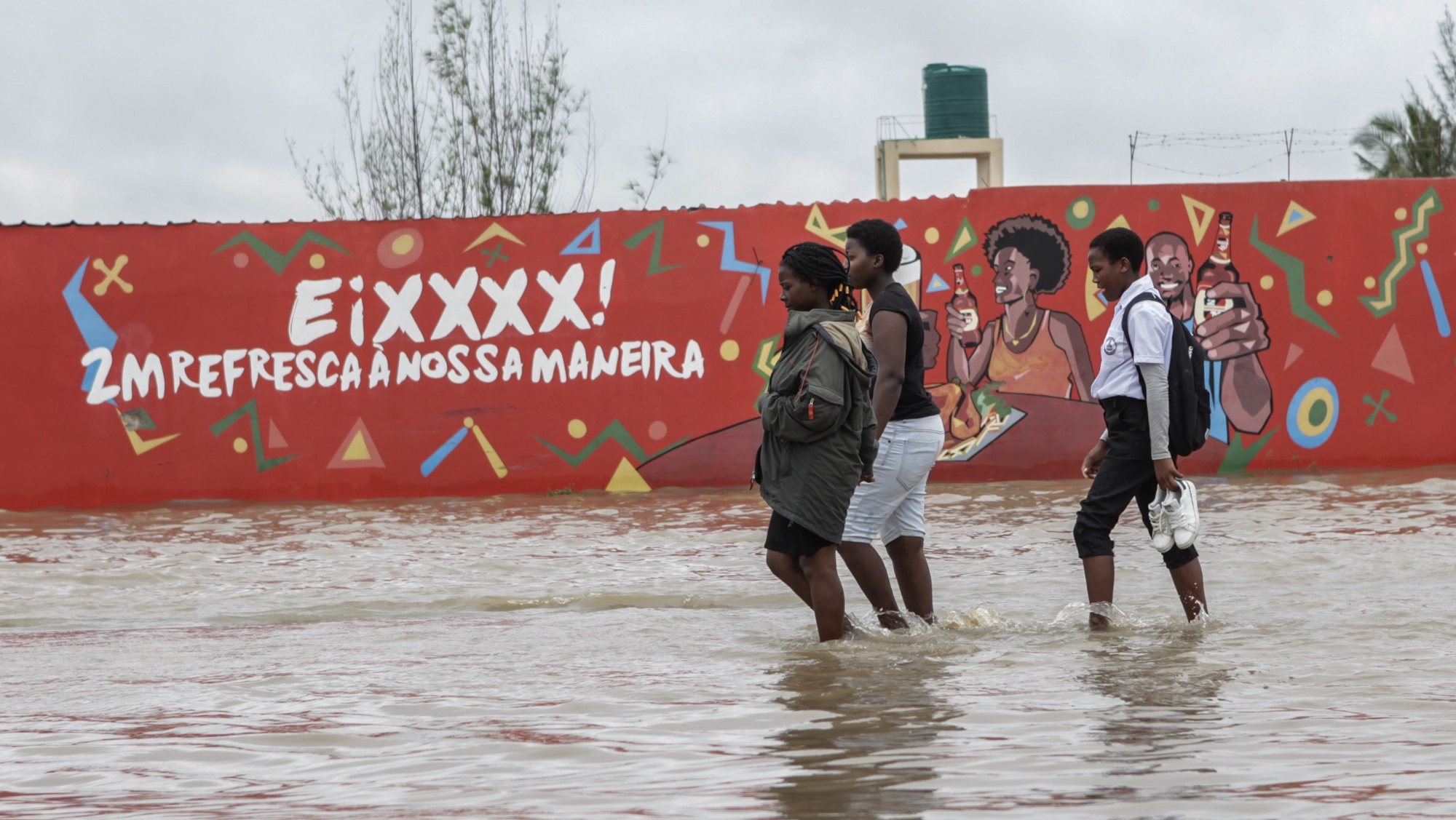 Populares passam por uma área inundada após chuvas desde 07 de Fevereiro em Maputo, Moçambique, 10 de fevereiro de 2023. A chuva intensa que cai na região de Maputo desde quarta-feira já afetou cerca de 14.000 pessoas e desalojou 180 famílias, de acordo com um balanço oficial divulgado hoje pelas autoridades, que mantêm em quatro o número de óbitos. LUÍSA NHANTUMBO/LUSA
