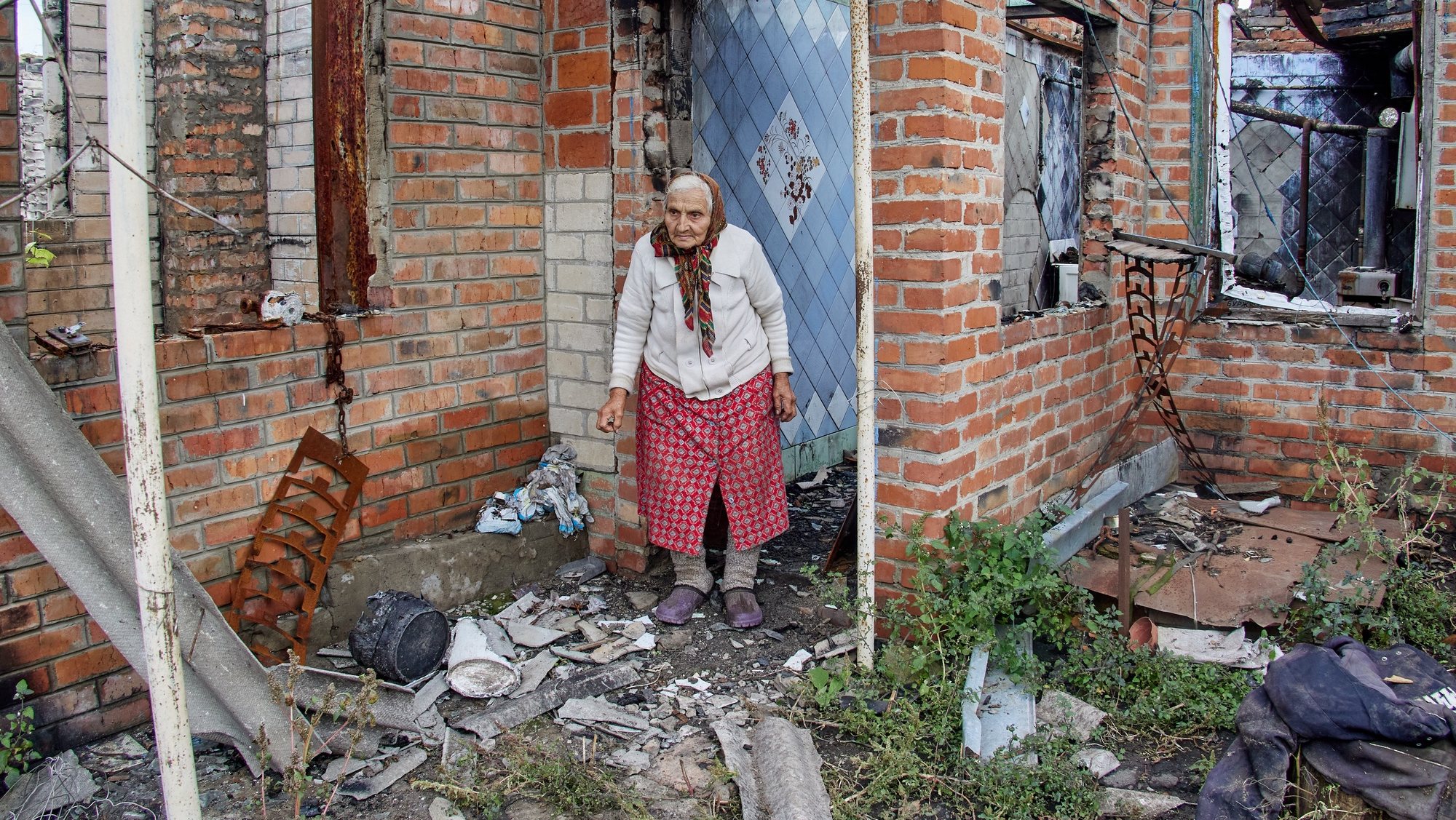 epa10218368 Nina Uspenskaya, stands next to her destroyed house following the Russian shelling, in the village of Korobochkyne, in the Kharkiv region, Ukraine, 01 October 2022. People in Ukraine are preparing for the winter season amid uncertainty over energy supplies. Kharkiv and surrounding areas have been the target of heavy shelling since February 2022, when Russian troops entered Ukraine starting a conflict that has provoked destruction and a humanitarian crisis.  EPA/SERGEY KOZLOV