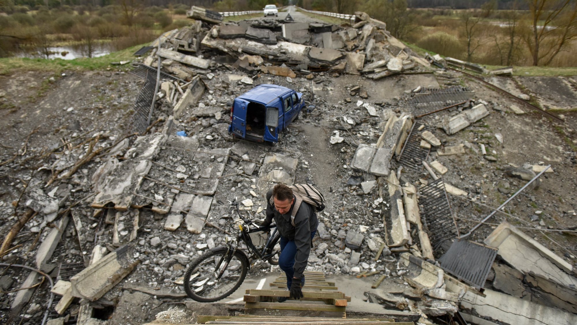 epa09897416 A man carries a bicycle over a destroyed bridge in Kyiv (Kiev) area, Ukraine, 19 April 2022. On 24 February Russian troops had entered Ukrainian territory resulting in fighting and destruction in the country, a huge flow of refugees, and multiple sanctions against Russia.  EPA/OLEG PETRASYUK