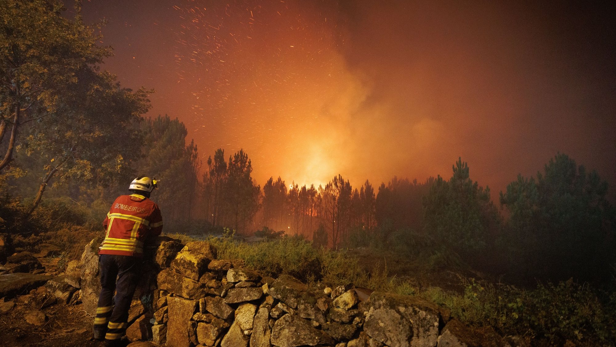 Um bombeiro observa as chamas durante o combate ao incêndio na aldeia de Escariz que se viu envolvida pelas chamas, esta tarde, em Vila Real, 21 de agosto 2022. PEDRO SARMENTO COSTA/LUSA