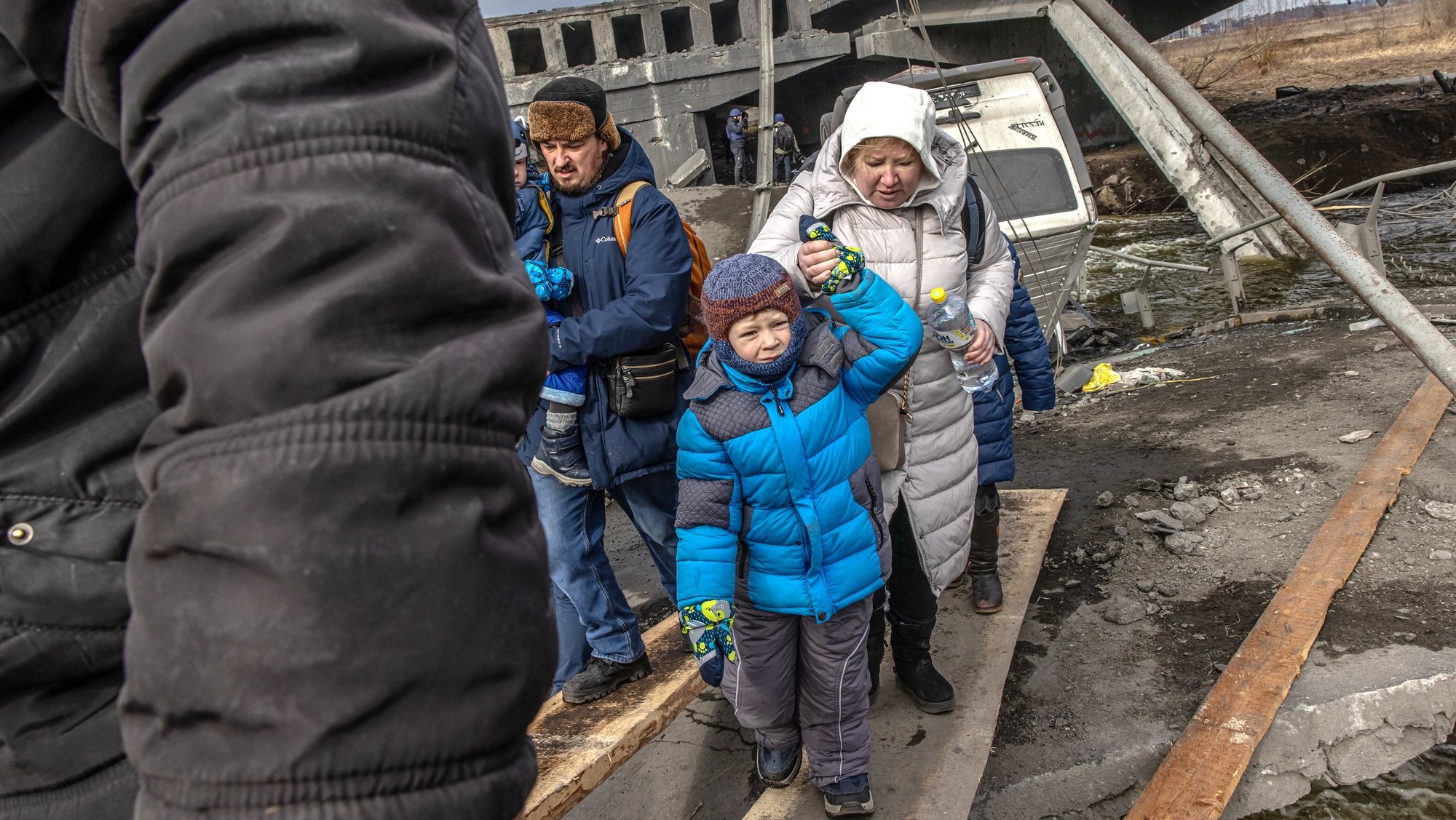 Crianças numa ponte destruída por bombardeamentos russos numa cidade perto de Kiev, na Ucrânia. 7 de março de 2022